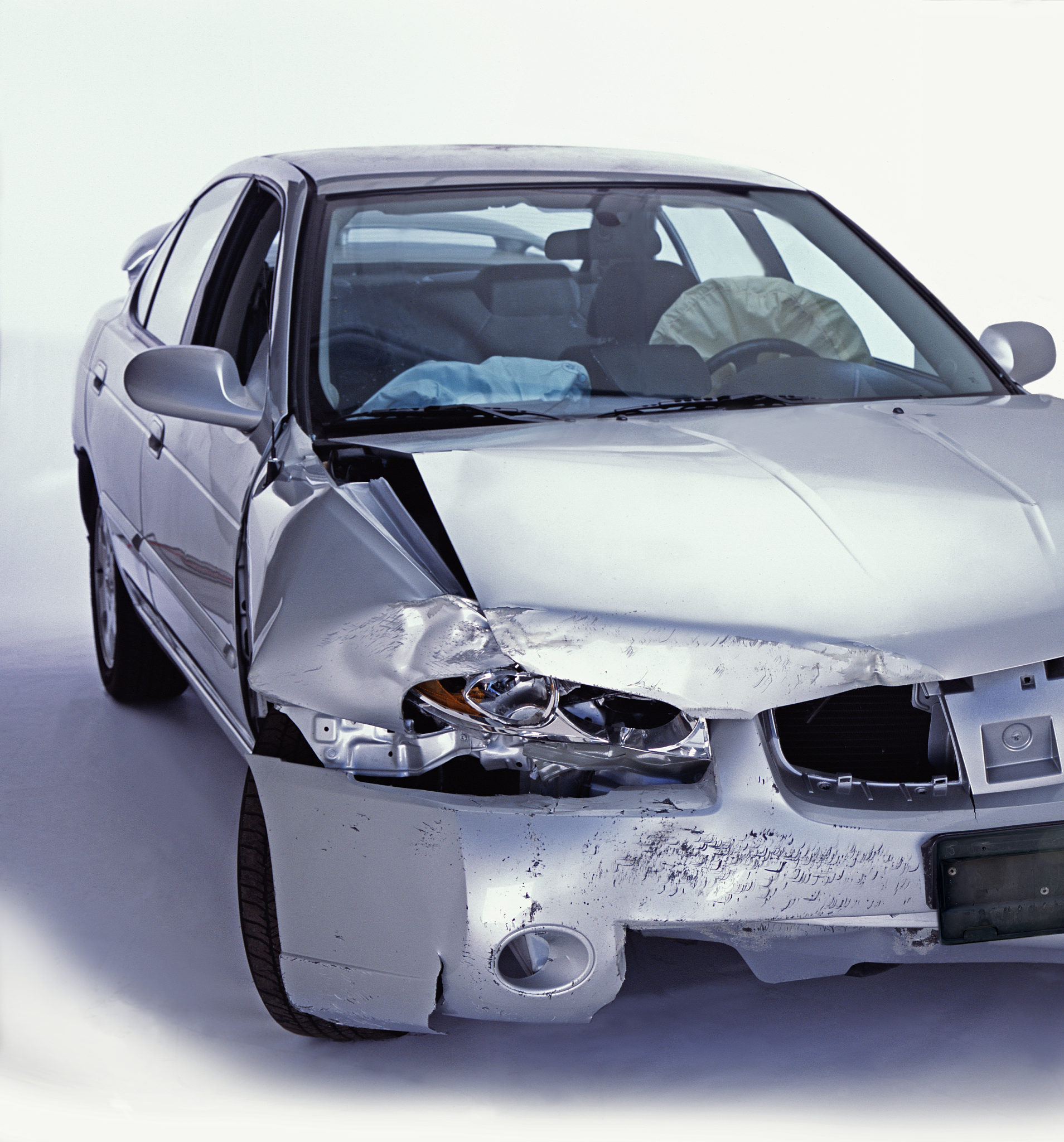silver sedan with front end damage and deployed airbags