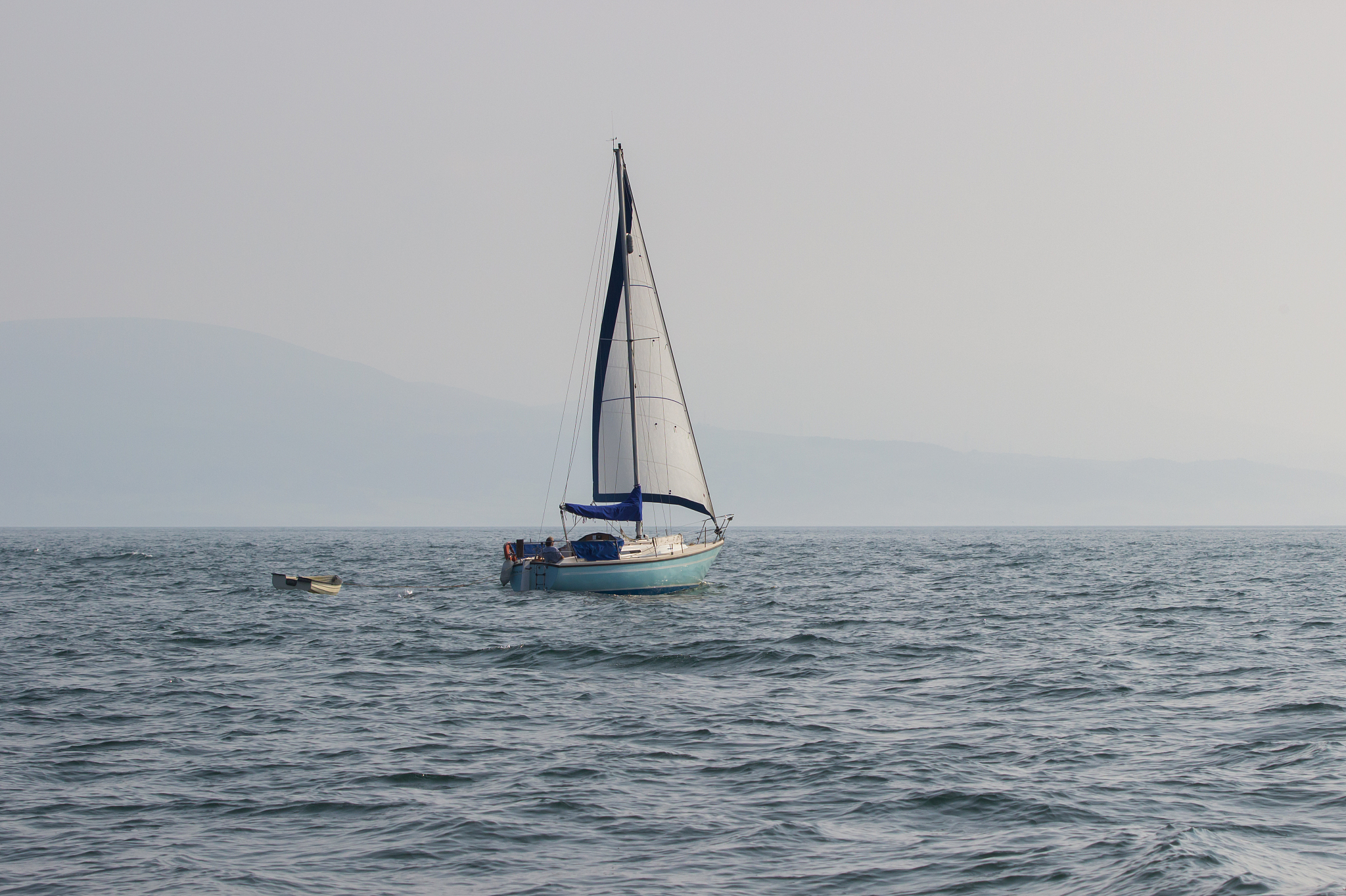 sailing boat with a white sail on the ocean in summer. blue sky 