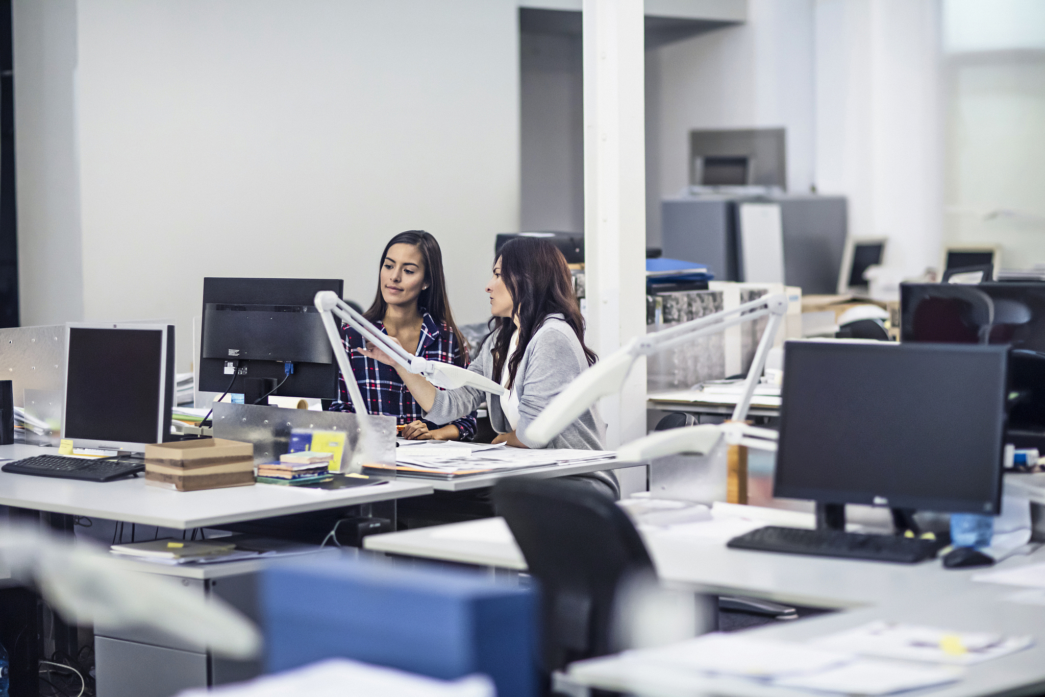 two women working together on computer at office