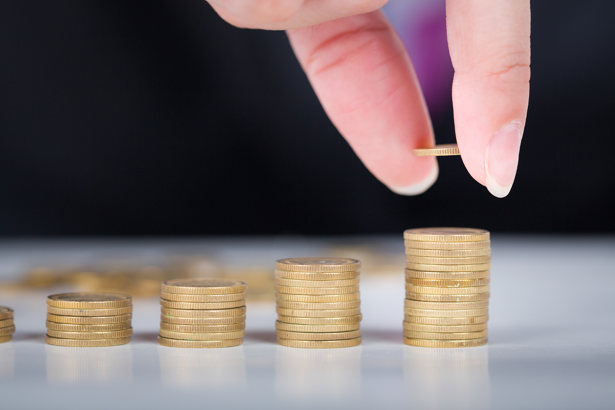 male hand fill money stack on gold coins bar
