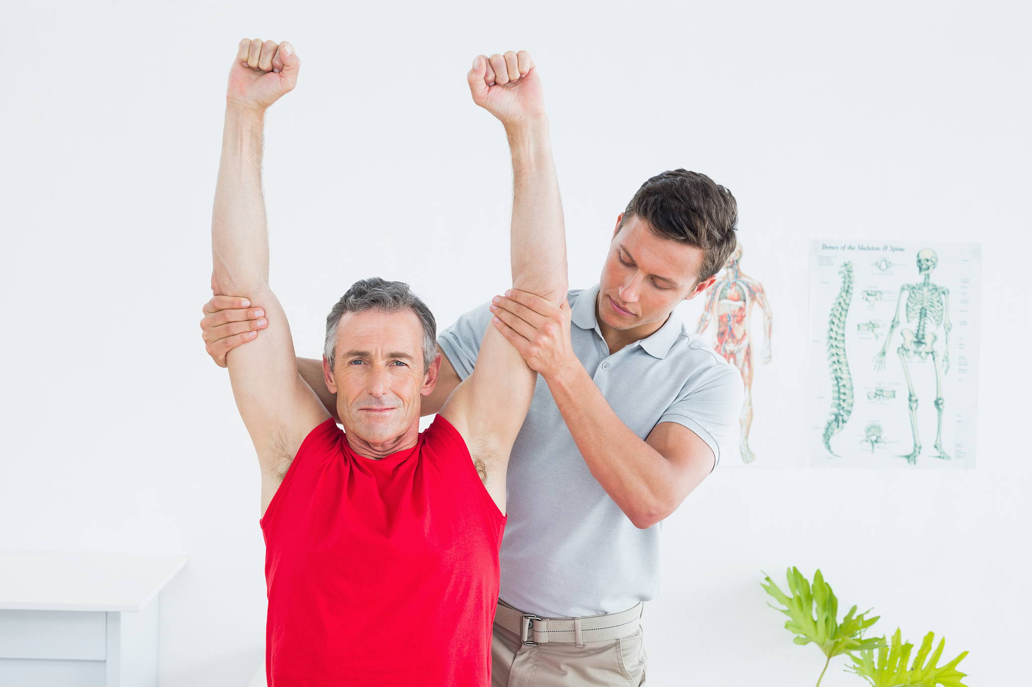 physiotherapist stretching a mature mans arms