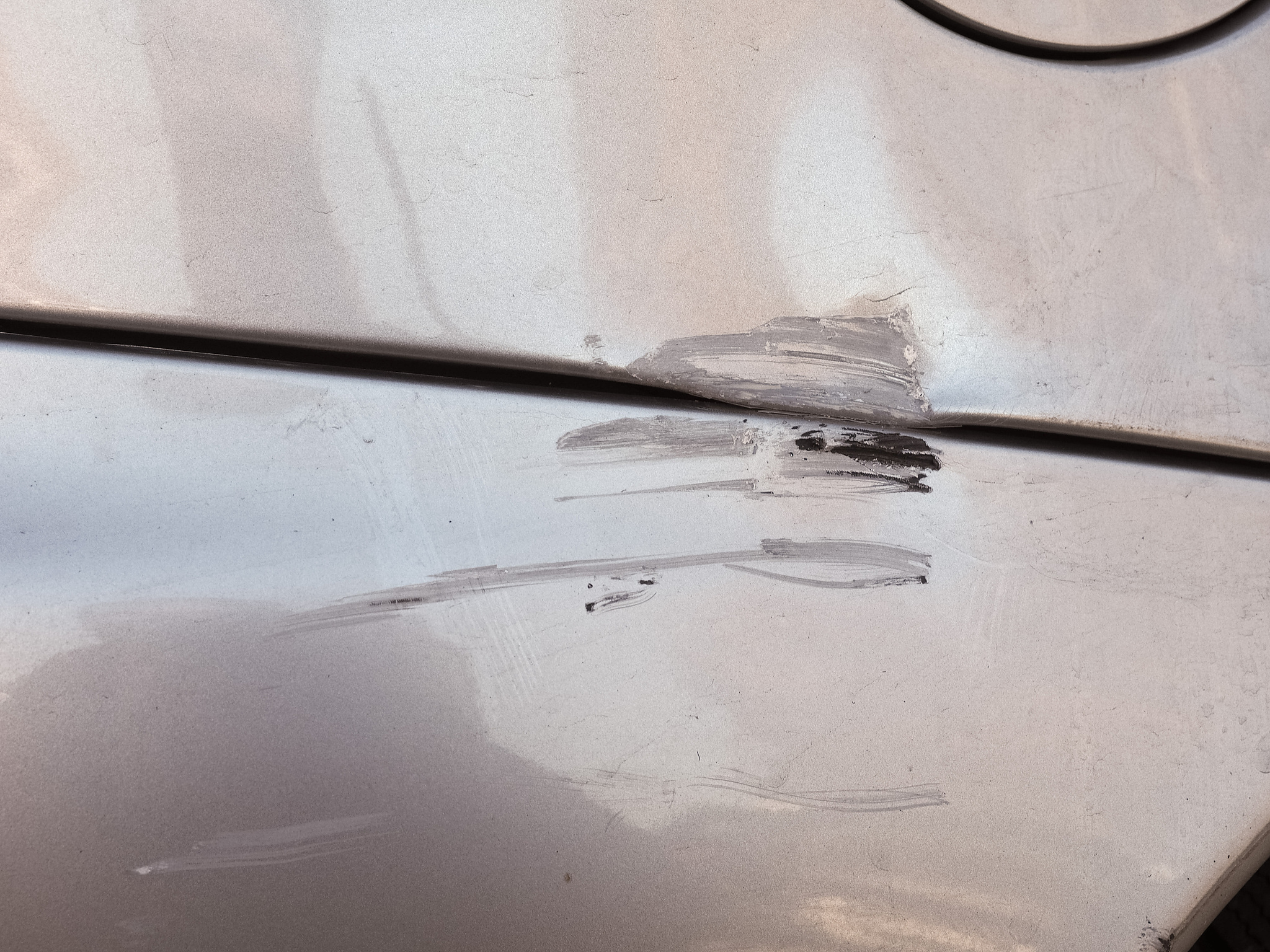 请翻译附近除了明显内凹变形和划痕外还有流下的油迹