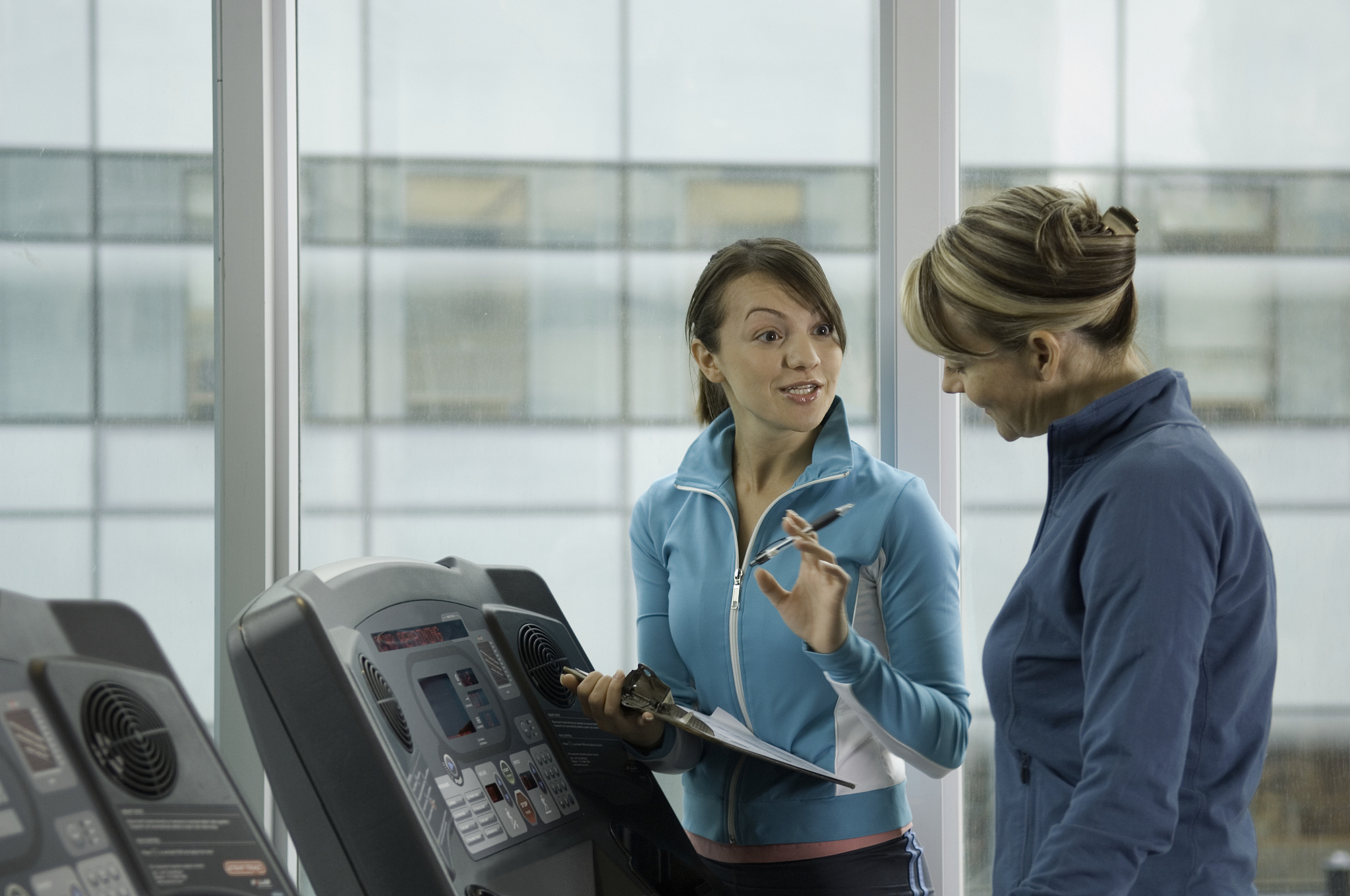 physical therapist monitoring mature woman in treadmill, smiling