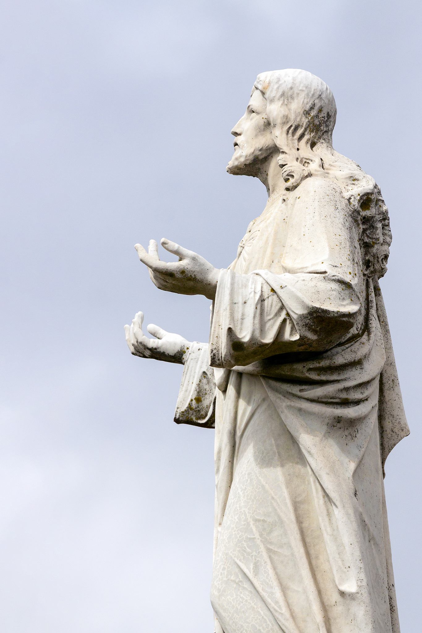 old staue of jesus christ, side view, sky background with copy s