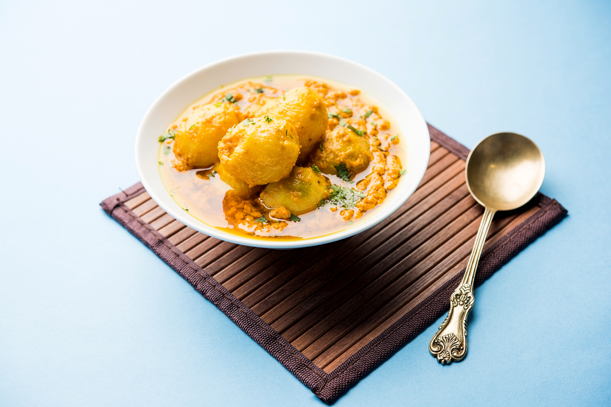 indian dum aloo curry using fried potatoes and spices, served in