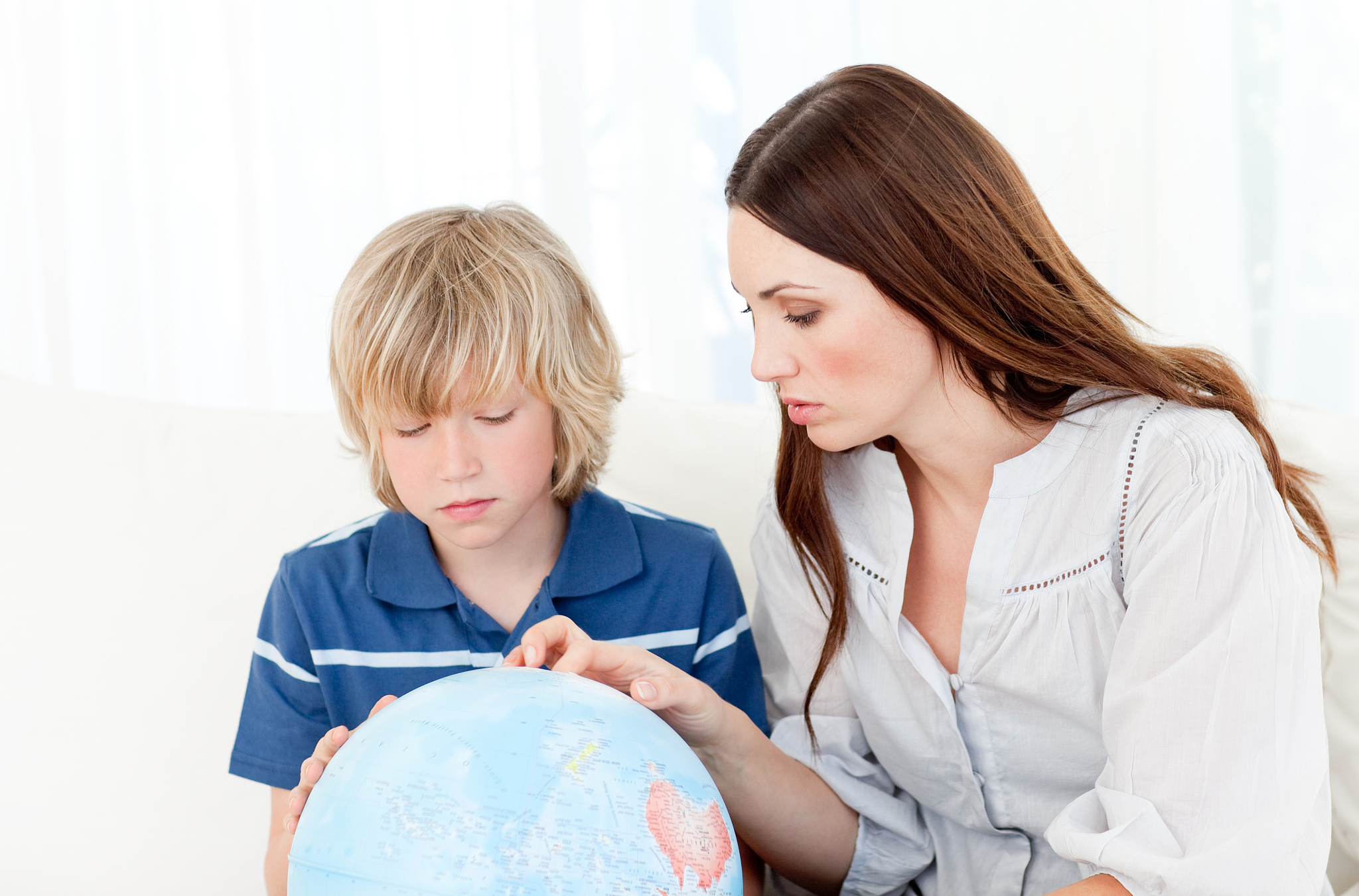 captivated child looking at a terrestrial globe with his mother