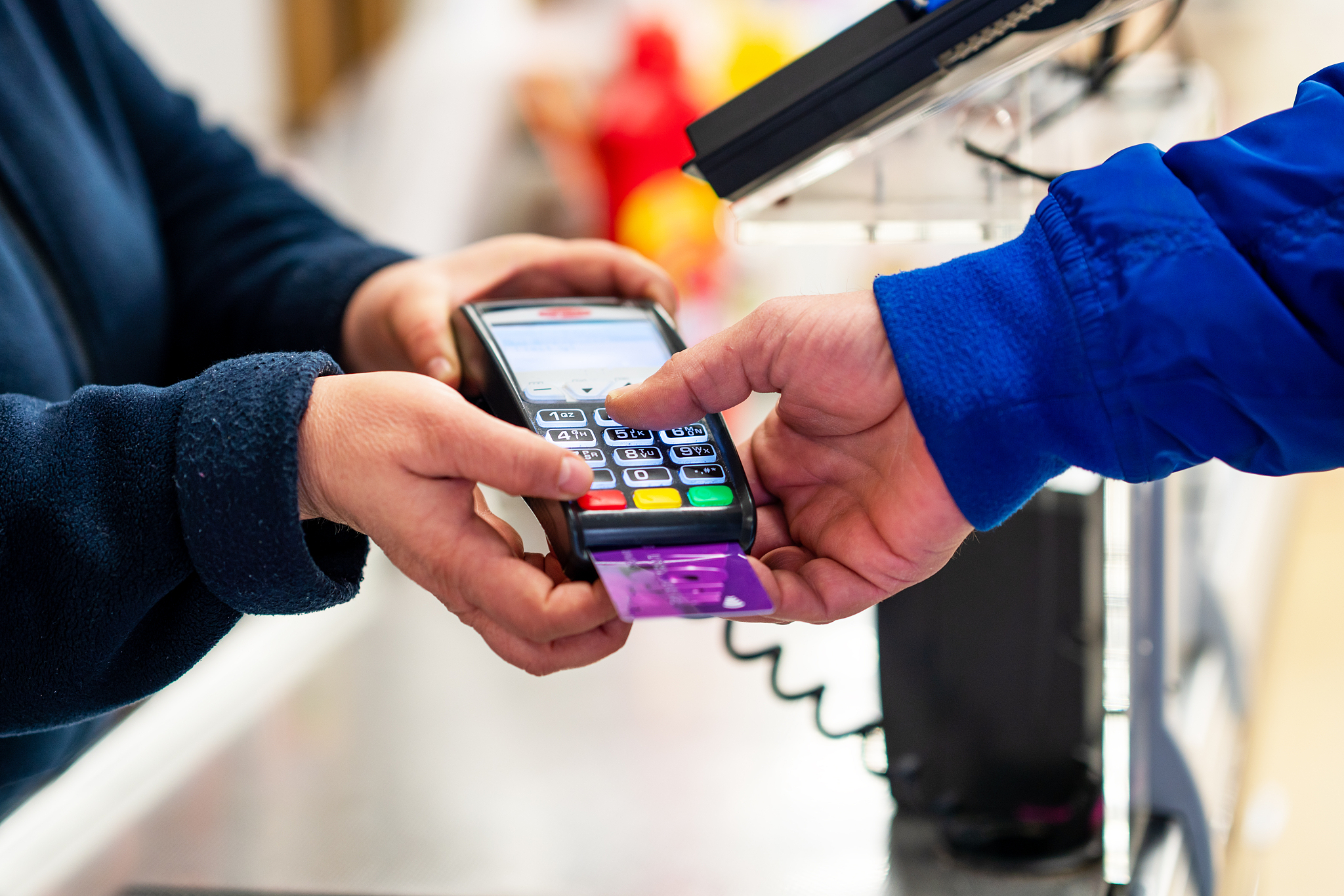 close up of using credit card pos terminal to pay. hands enterin