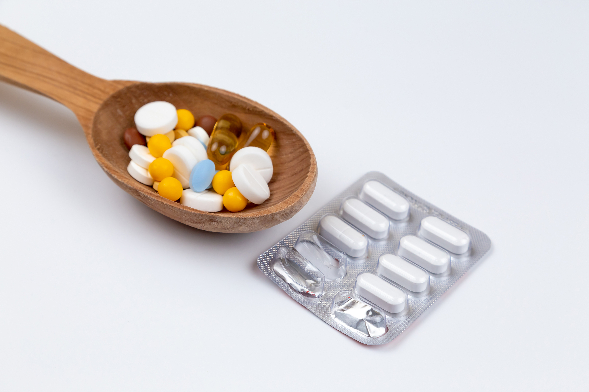 medicine, pills and drug in wood spoon on white background with 