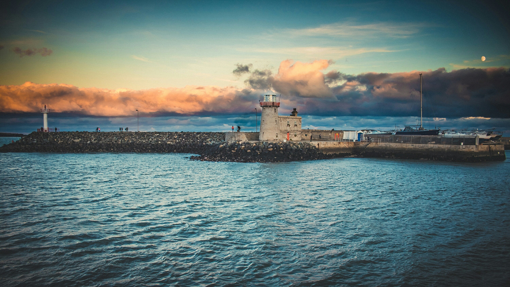 sea and lighthouse against cloudy sky during sunset