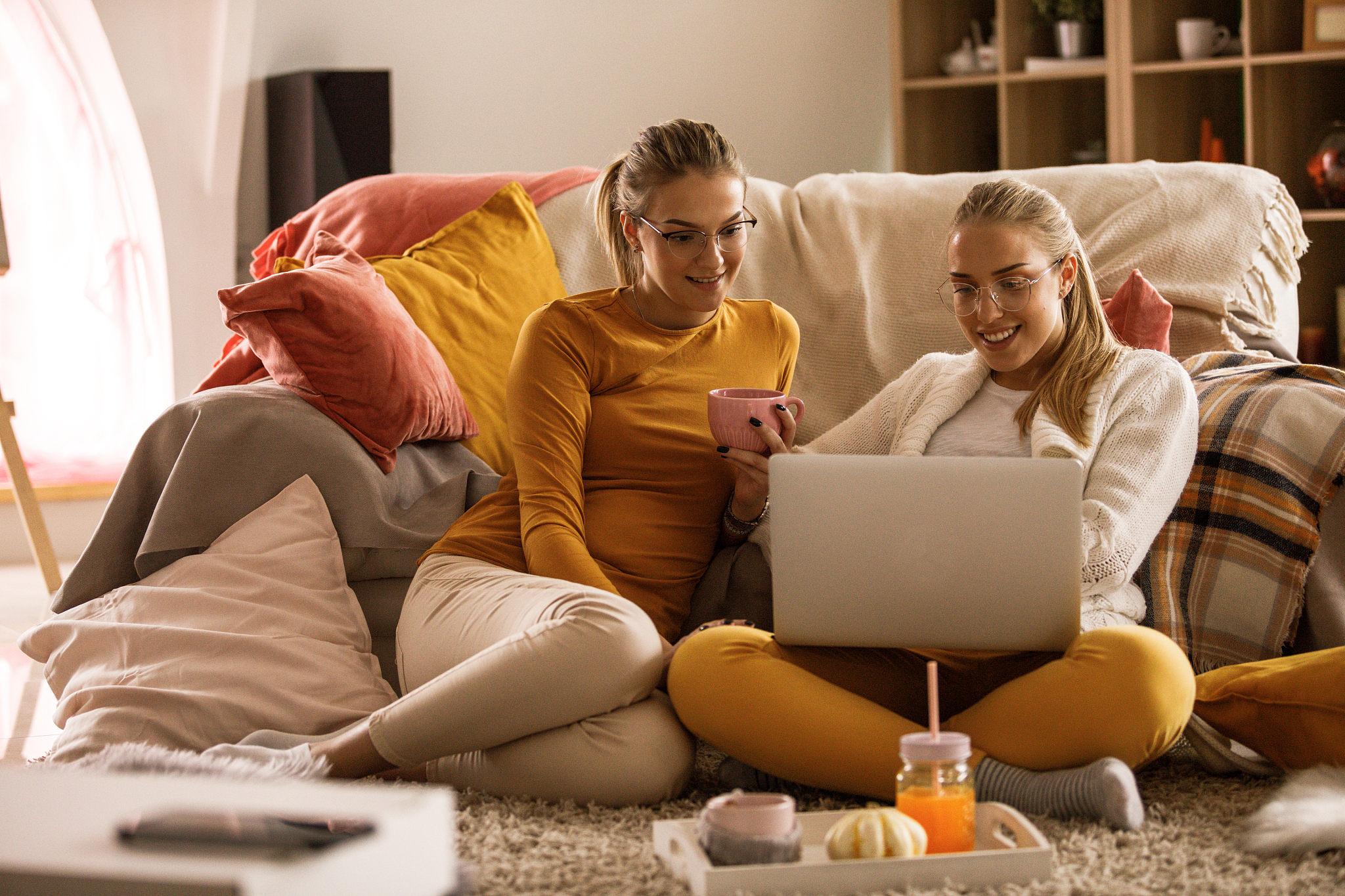 two smiling young women watching a movie on a laptop and relaxin