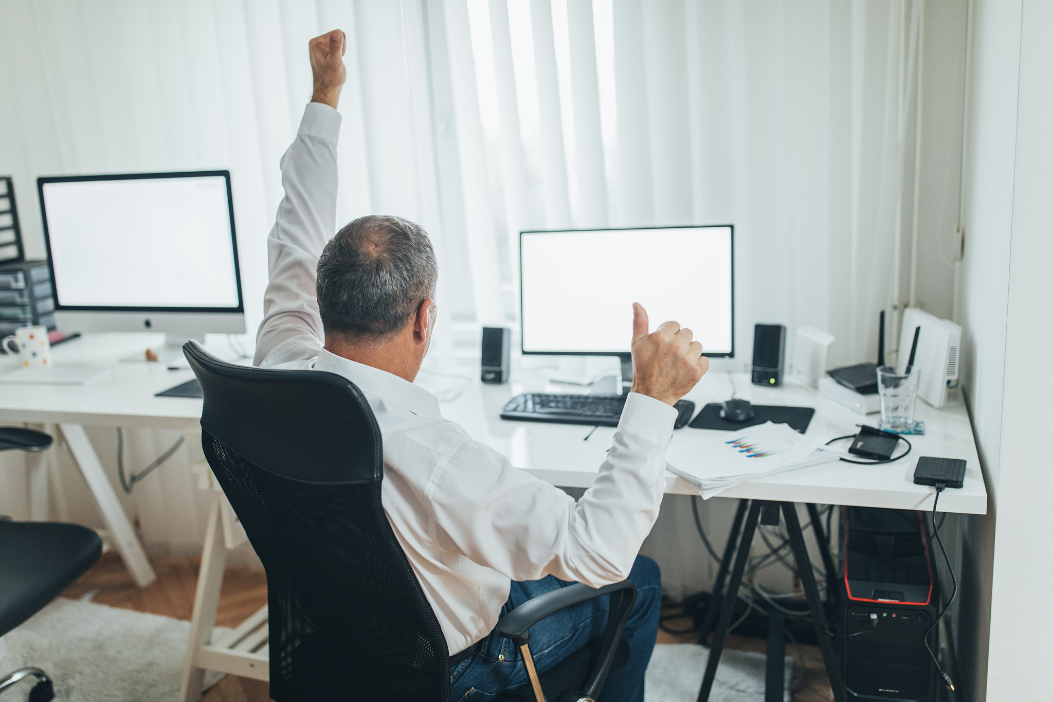 senior office worker celebrates in front of computer