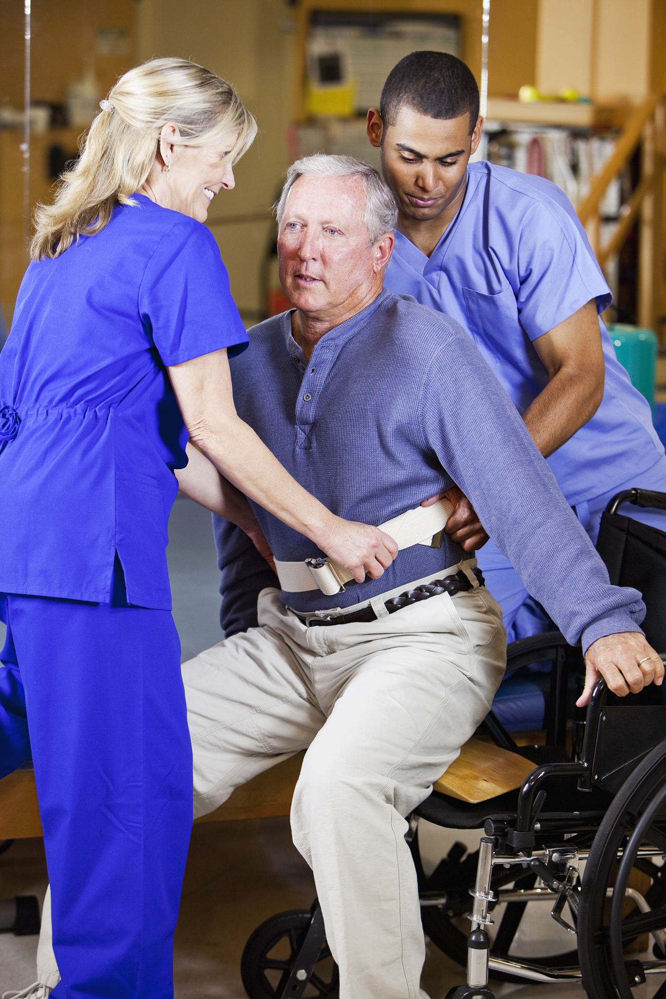 physical therapists helping patient into wheelchair
