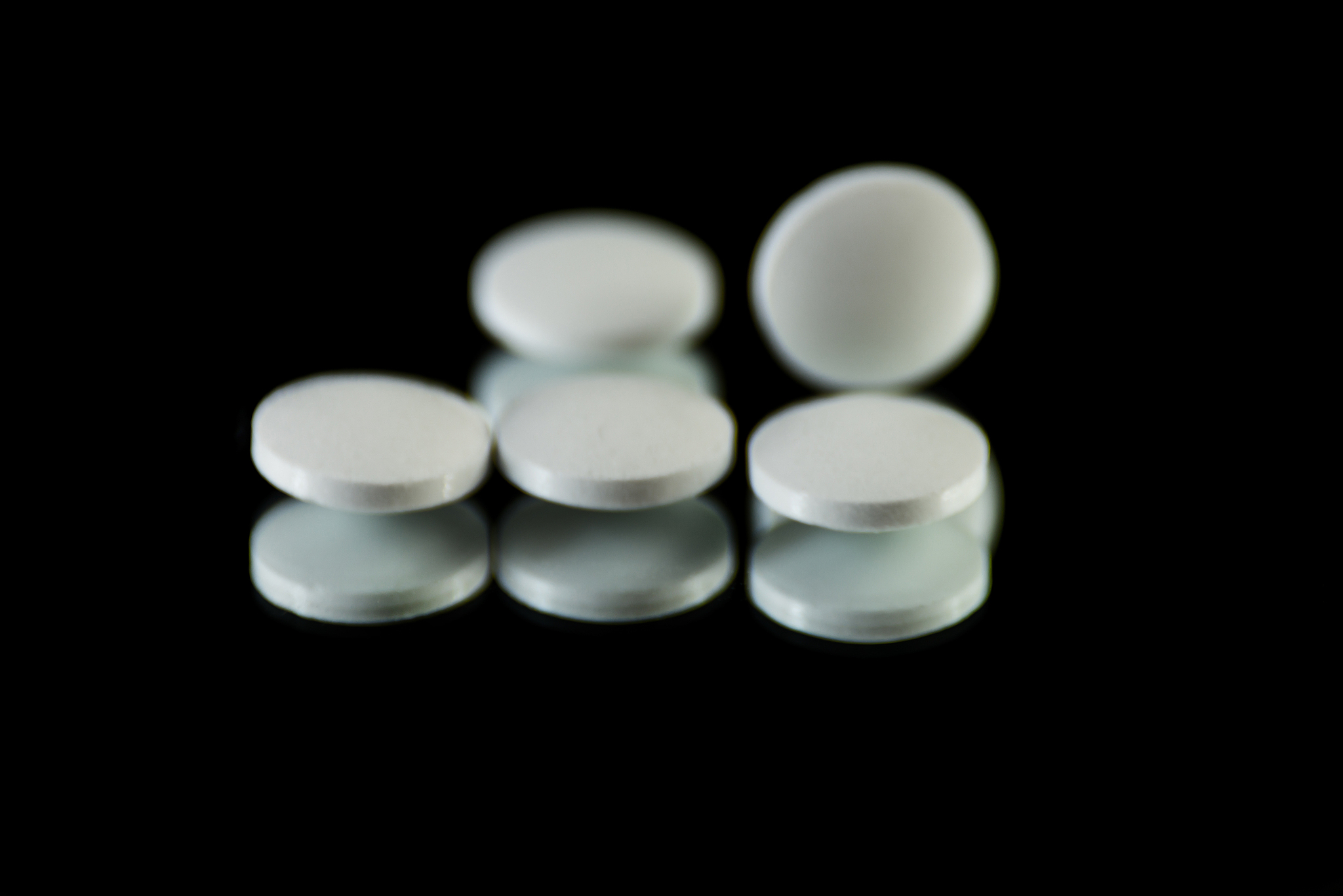 scattered tablets on a black background, pills reflected in the 