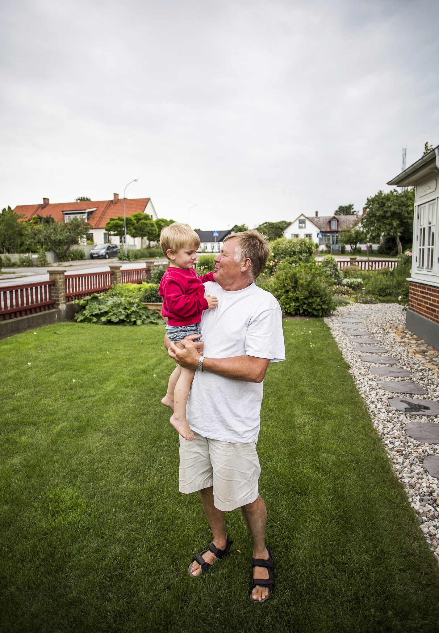 happy senior man carrying grandson at lawn
