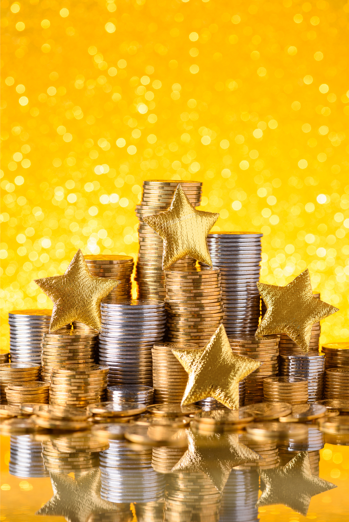 golden and silver coins stacked with shiny golden stars