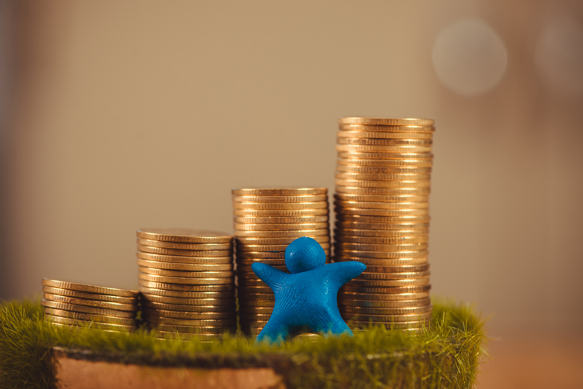miniature human figure made from blue plasticine with coins on w