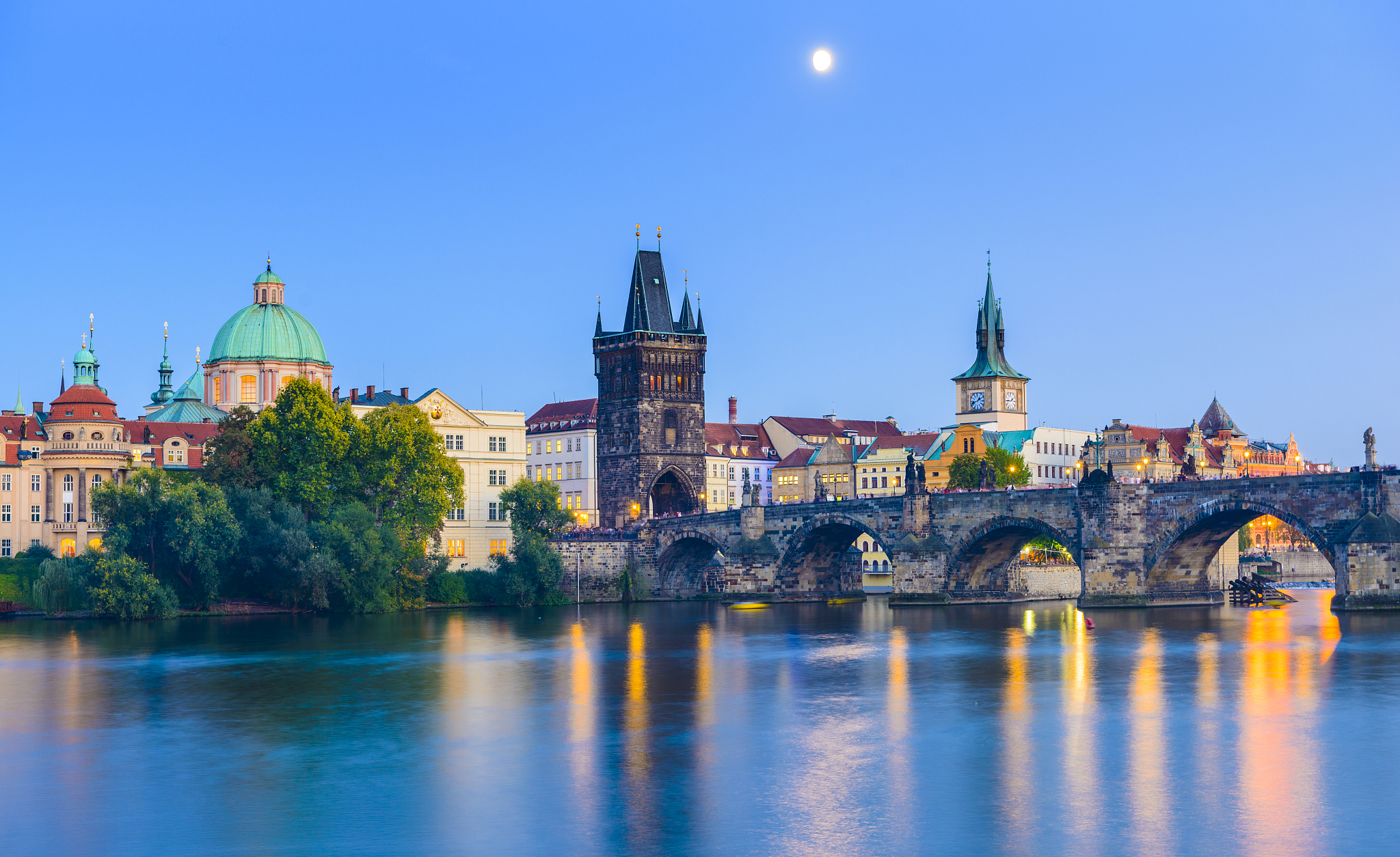 the charles bridge in prague at twilight with the moon visible i