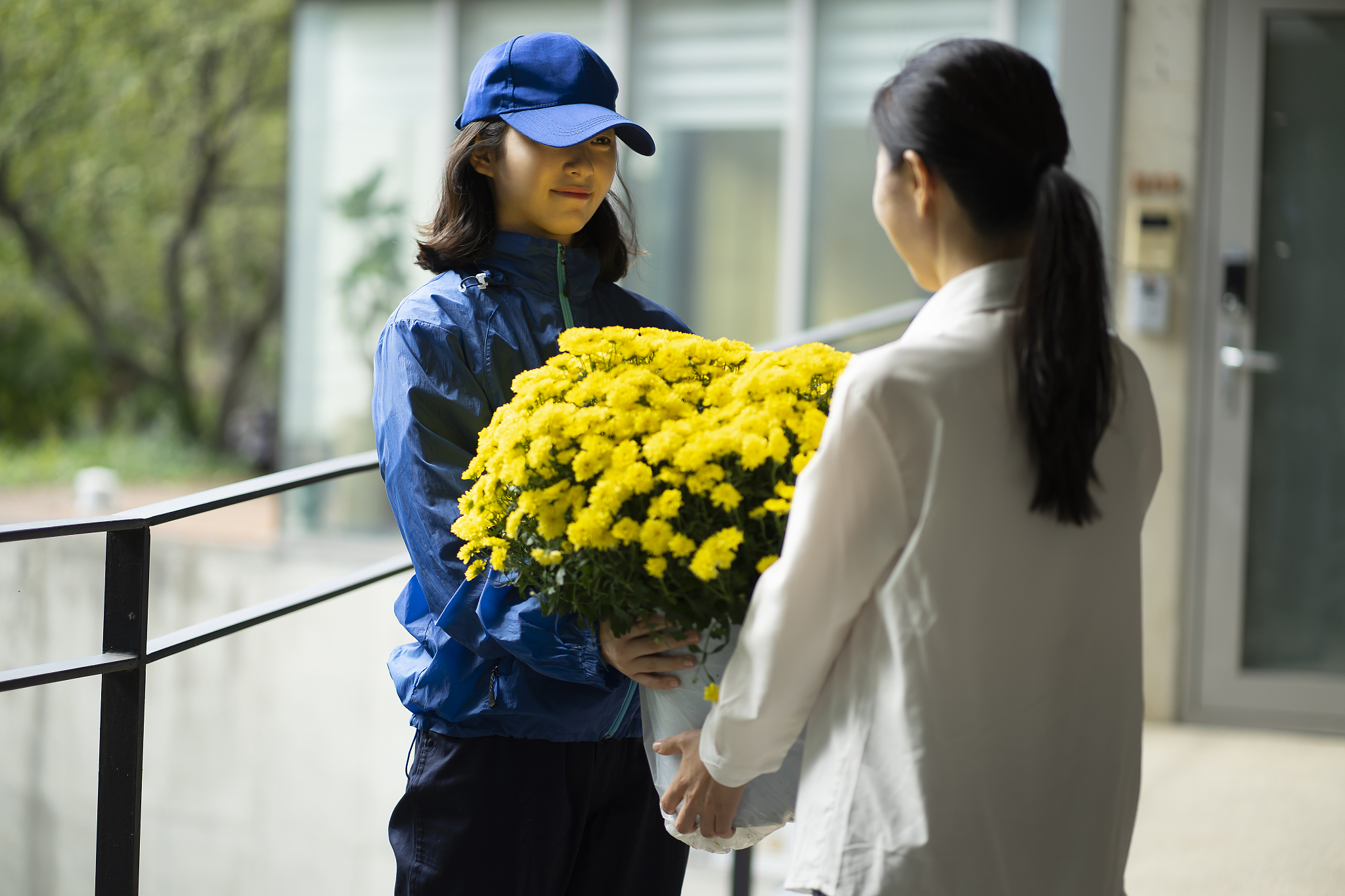 delivery person delivering flower pot to woman