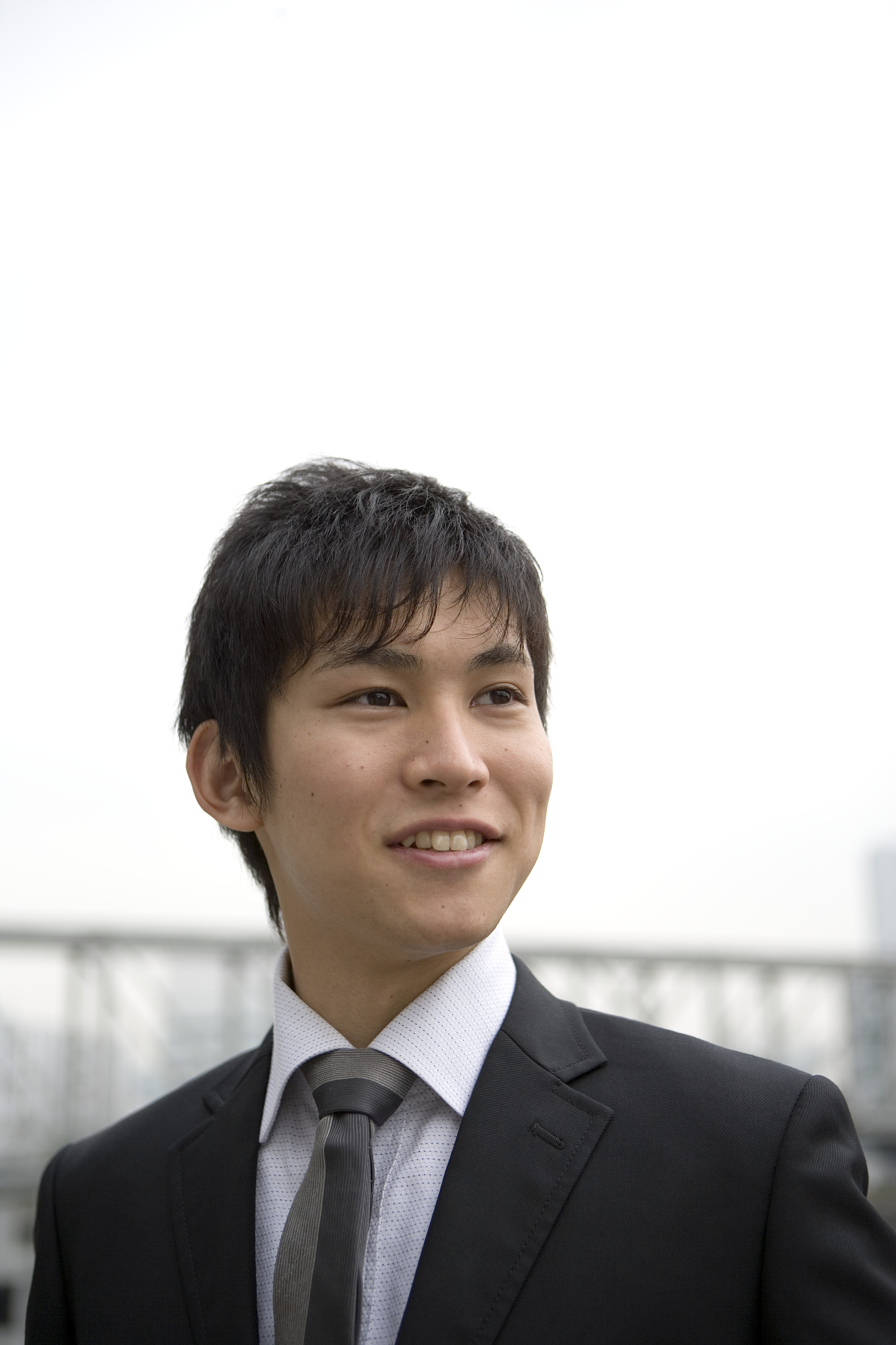 young businessman outdoors, looking to side, smiling
