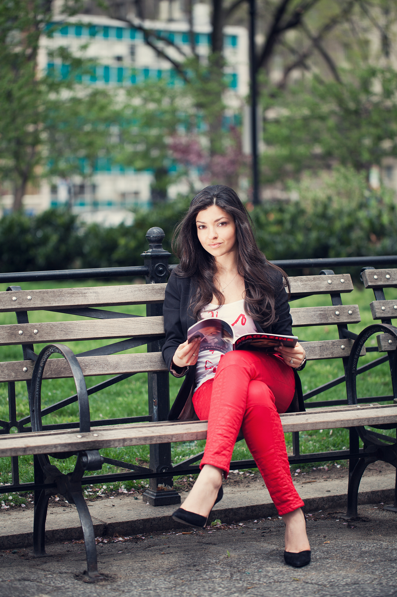 young woman with magazine in park looking at camera