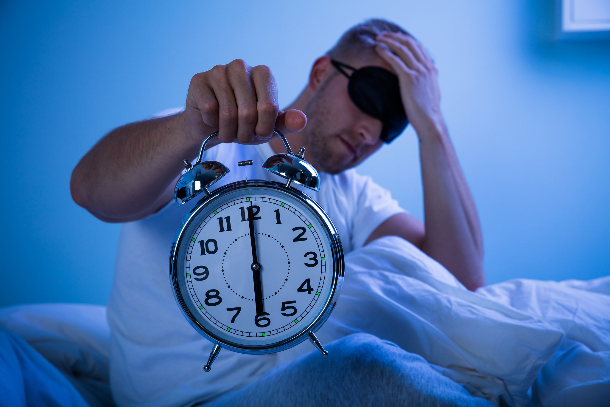 man sleeping with a alarm clock in his hand