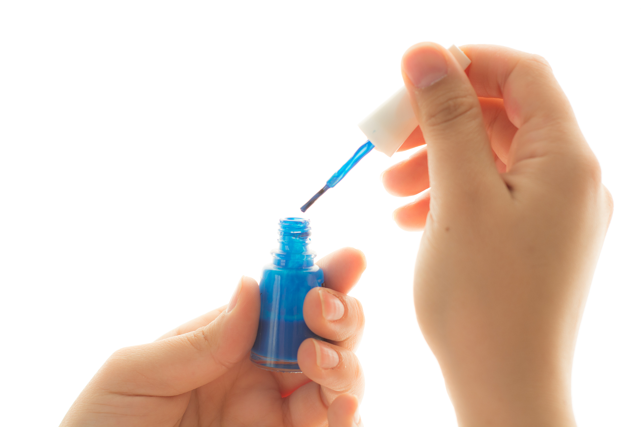 cropped hand of woman holding nail polish against white backgrou