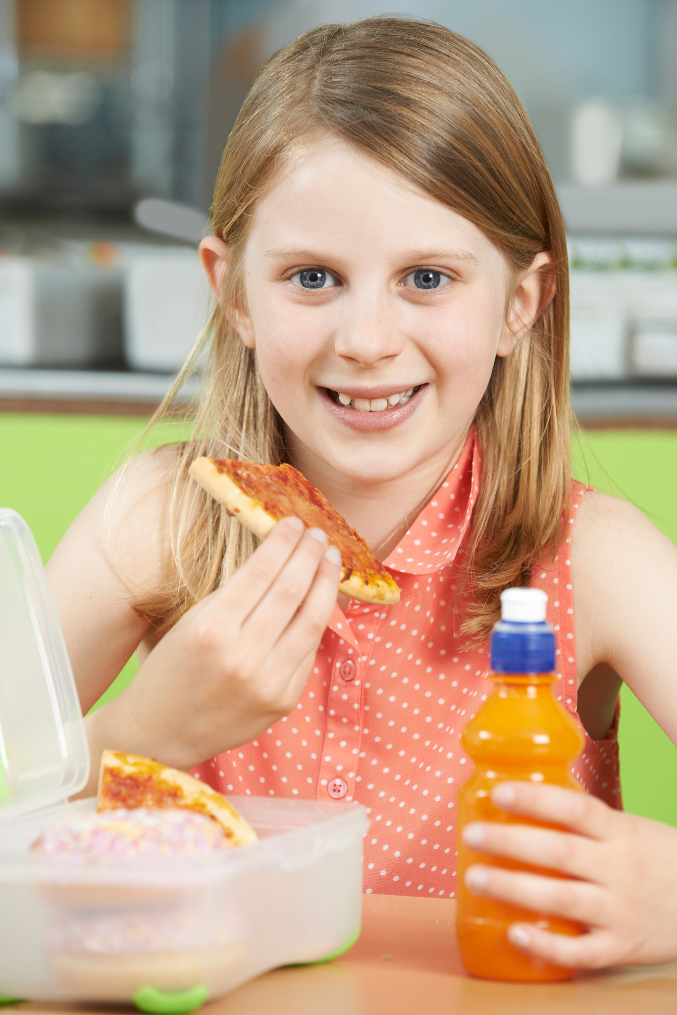 female pupil sitting at table in school cafeteria eating unhealt