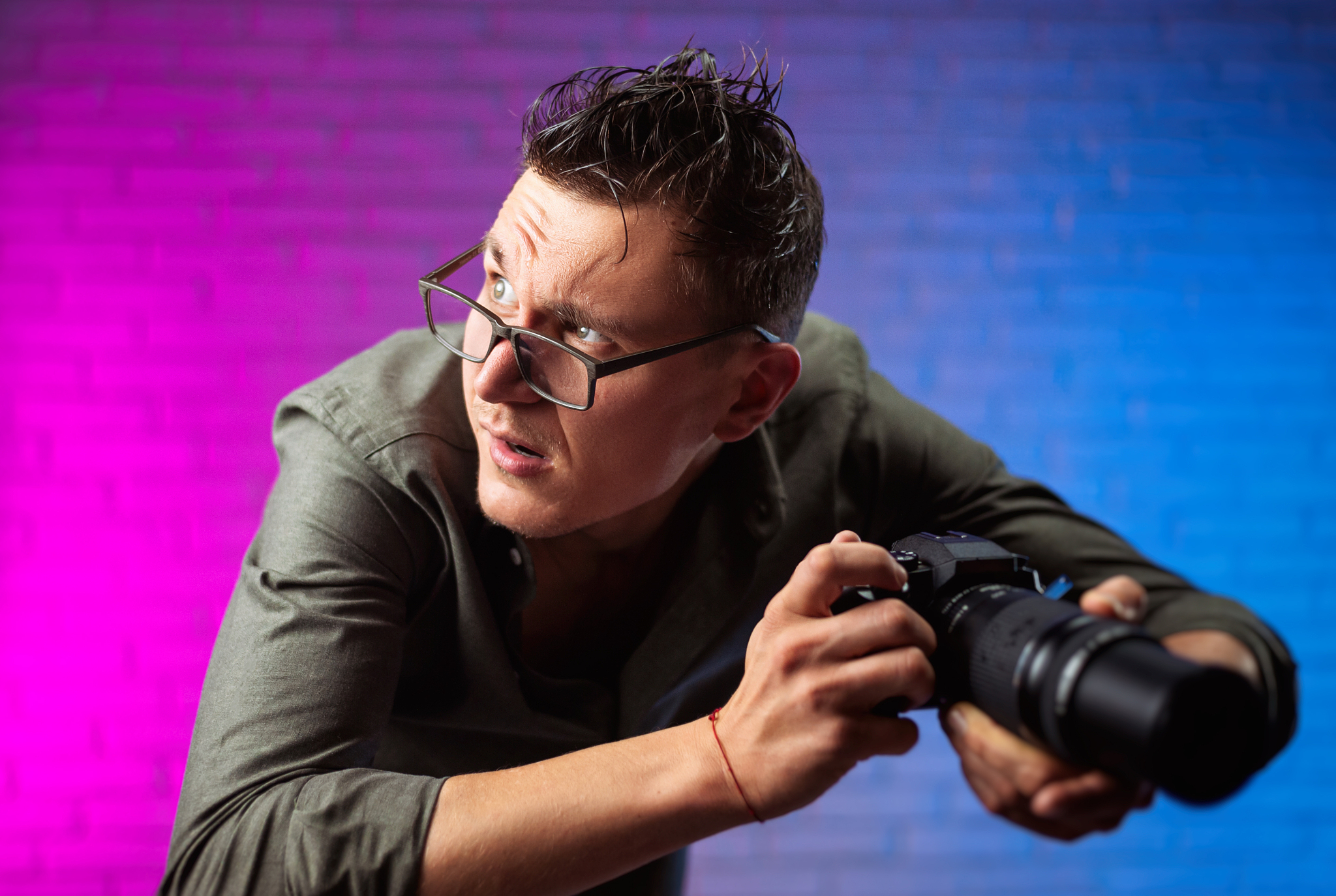 crazy man in glasses with a digital camera on a bright neon back