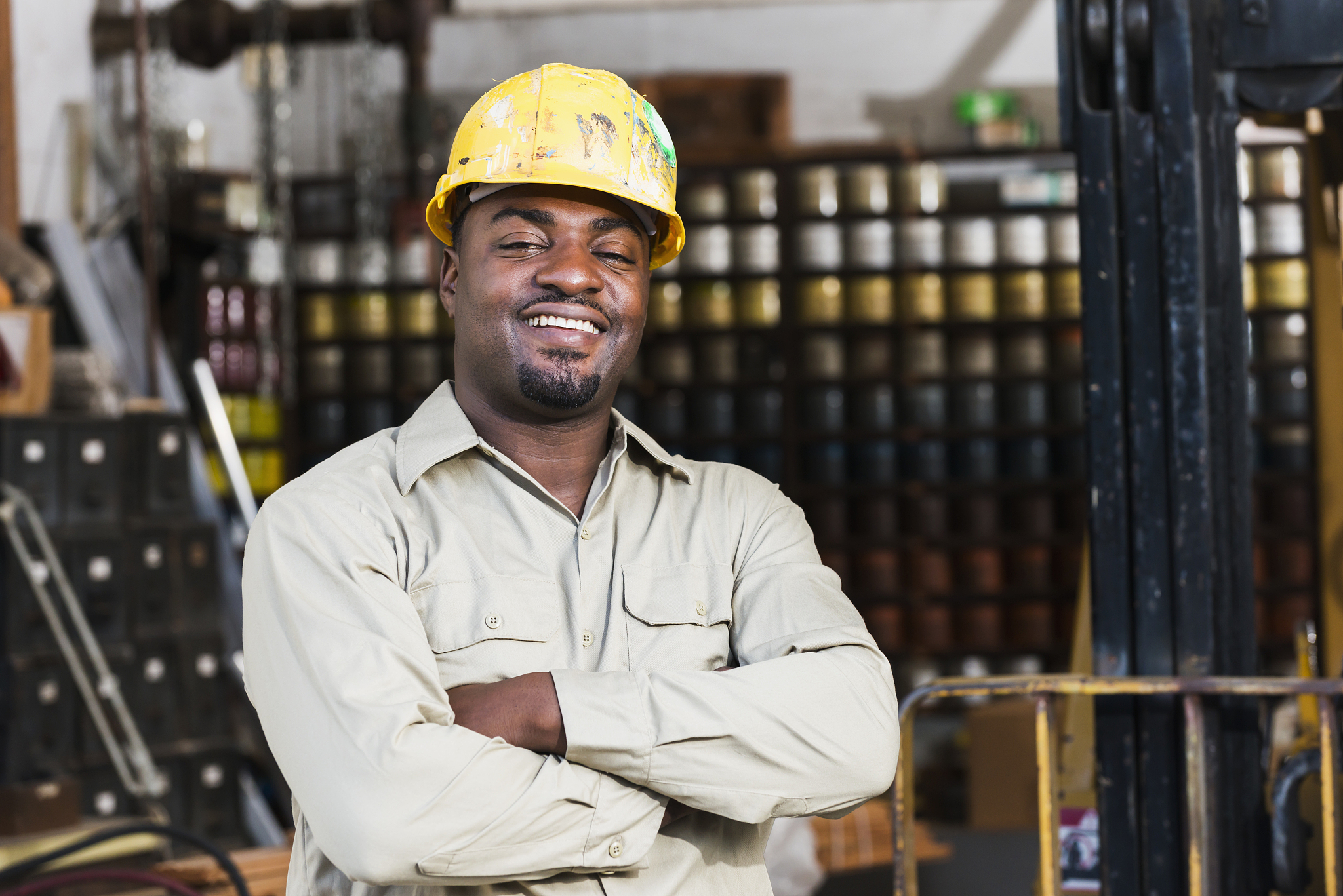african american worker in print shop, next to forklift