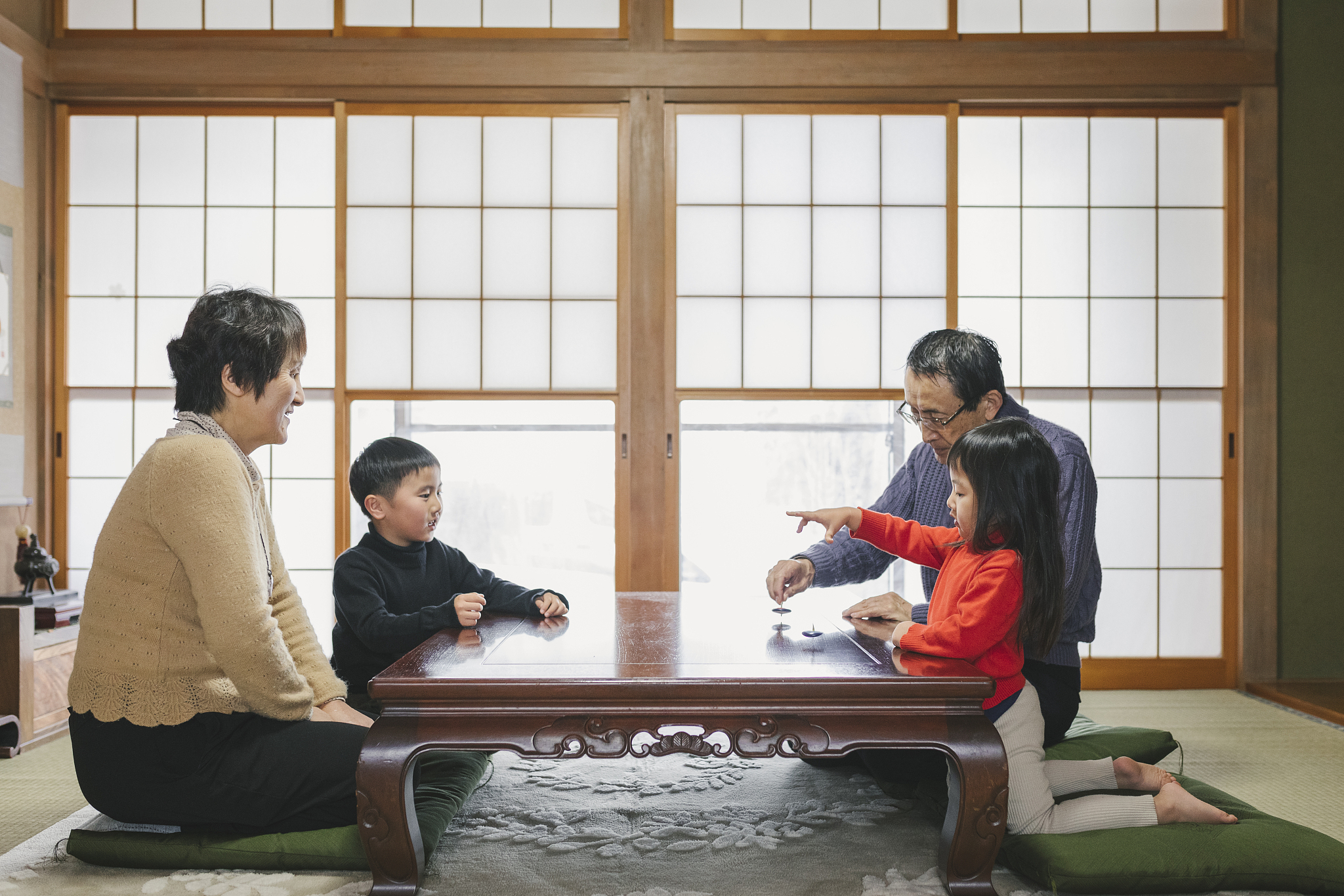 asian multi generation family playing spinning a top together