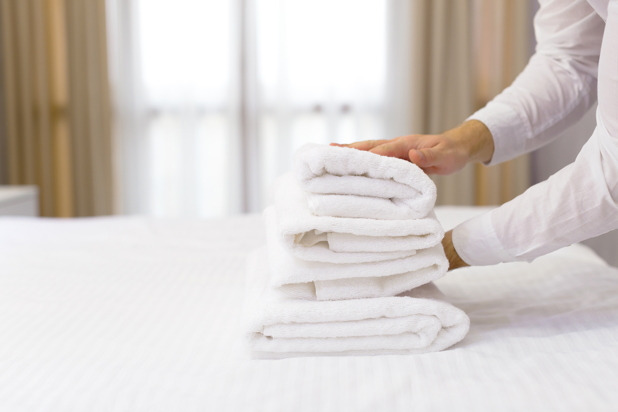 hotel staff setting up pillow on bed