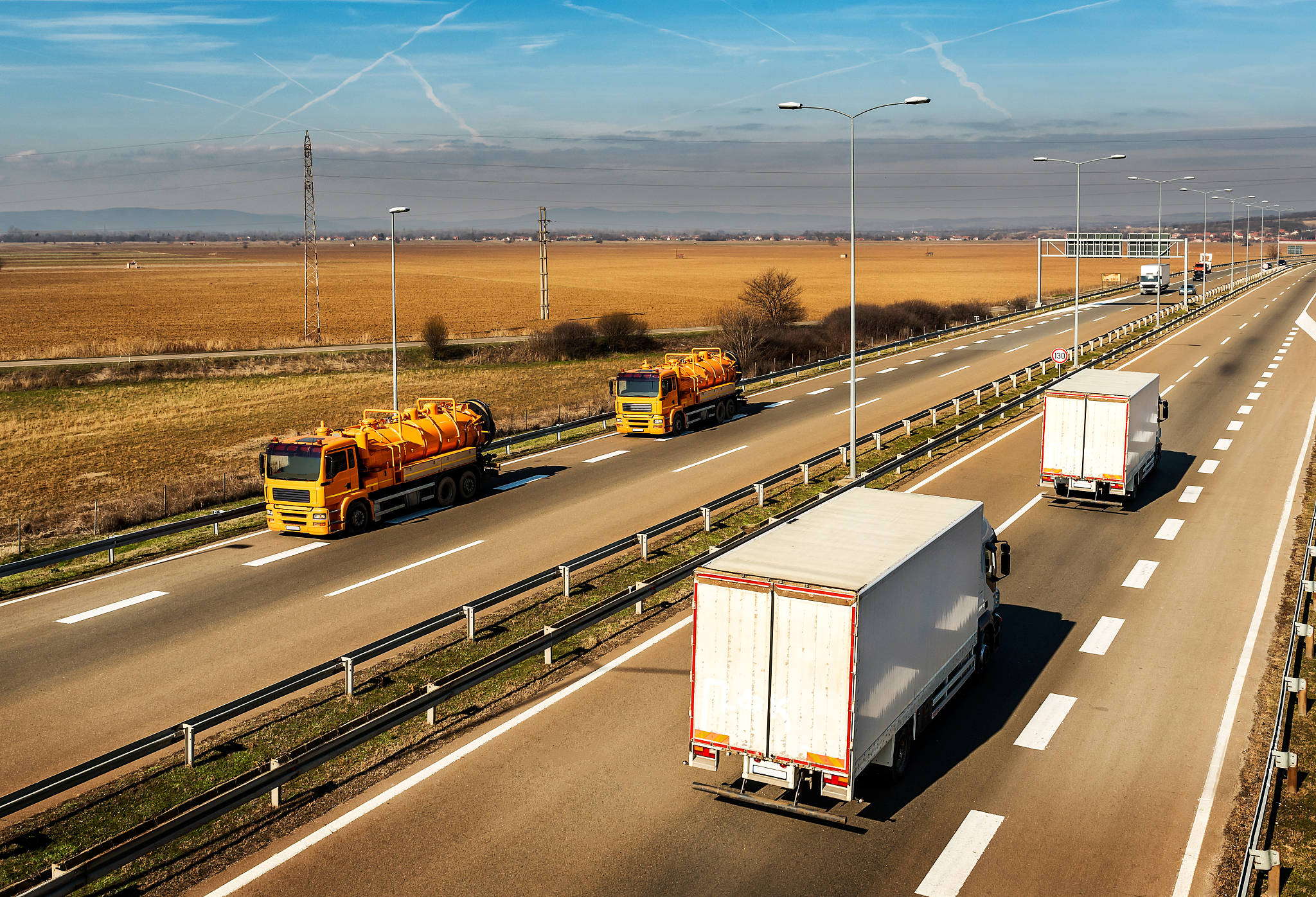 two orange tank trucks or cisterns on a highway road passing whi