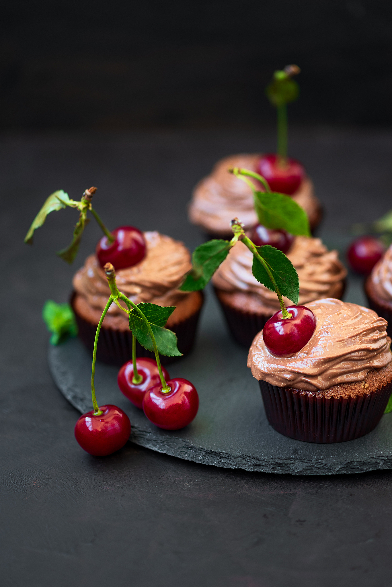 chocolate cupcakes with ripe red cherries on dark wooden backgro