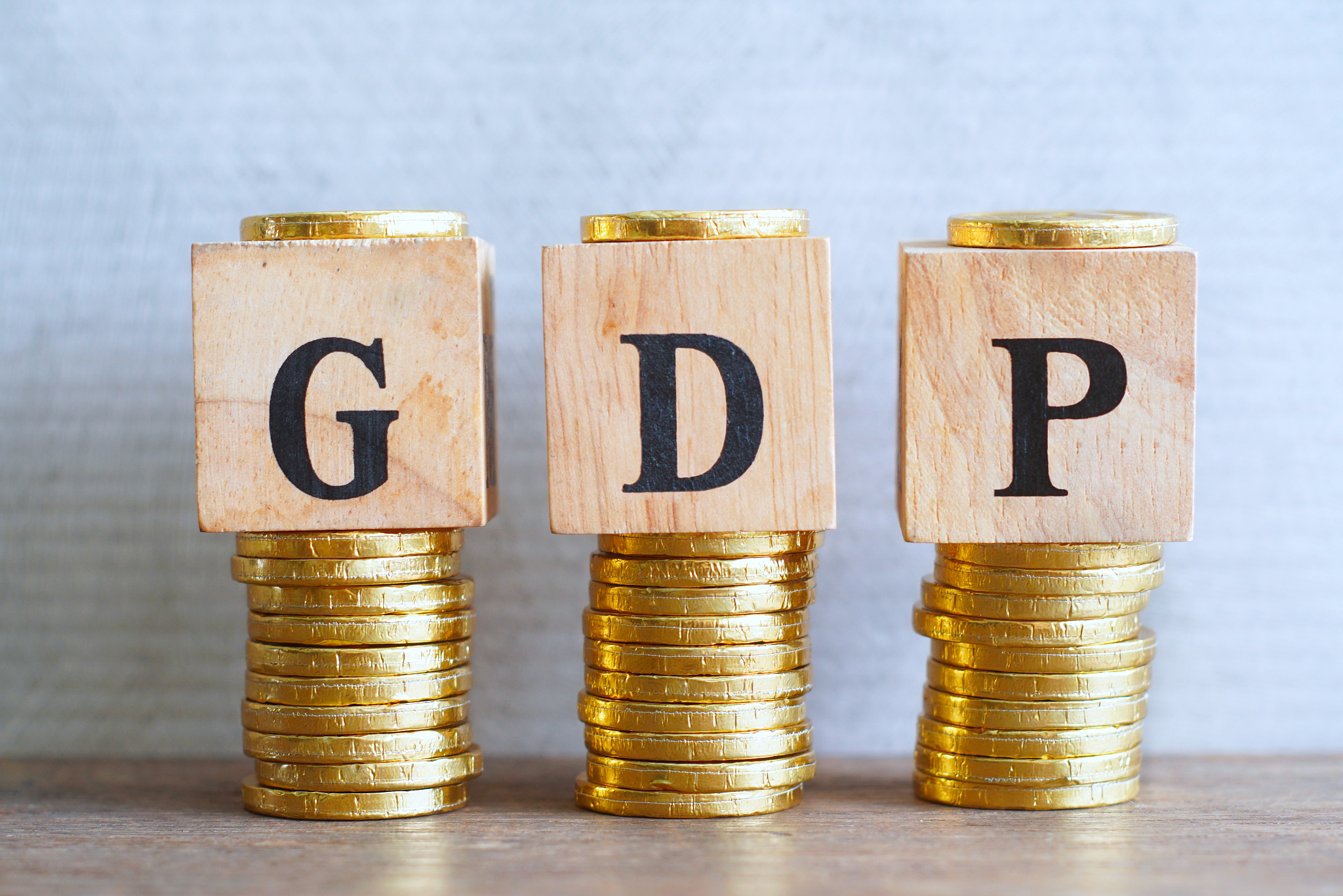 text "gdp" on wood cube lay on gold coins stack, economic data c