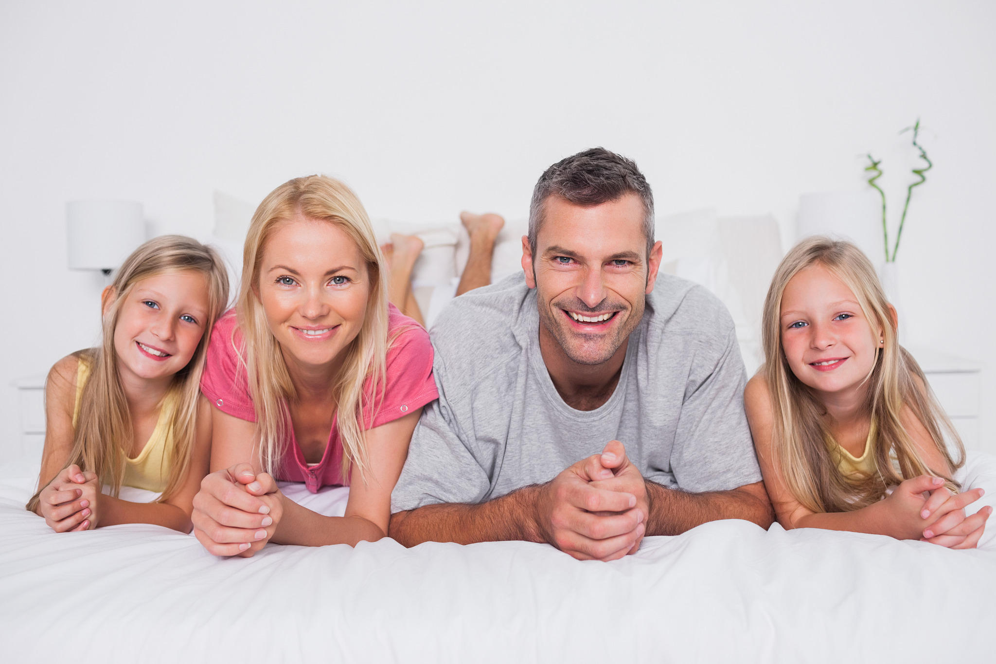 parents lying in bed with their cute children