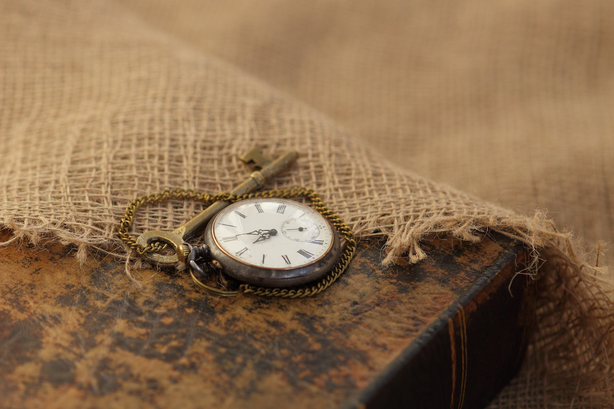 ancient pocket watch and key on old folio half-covered with old 