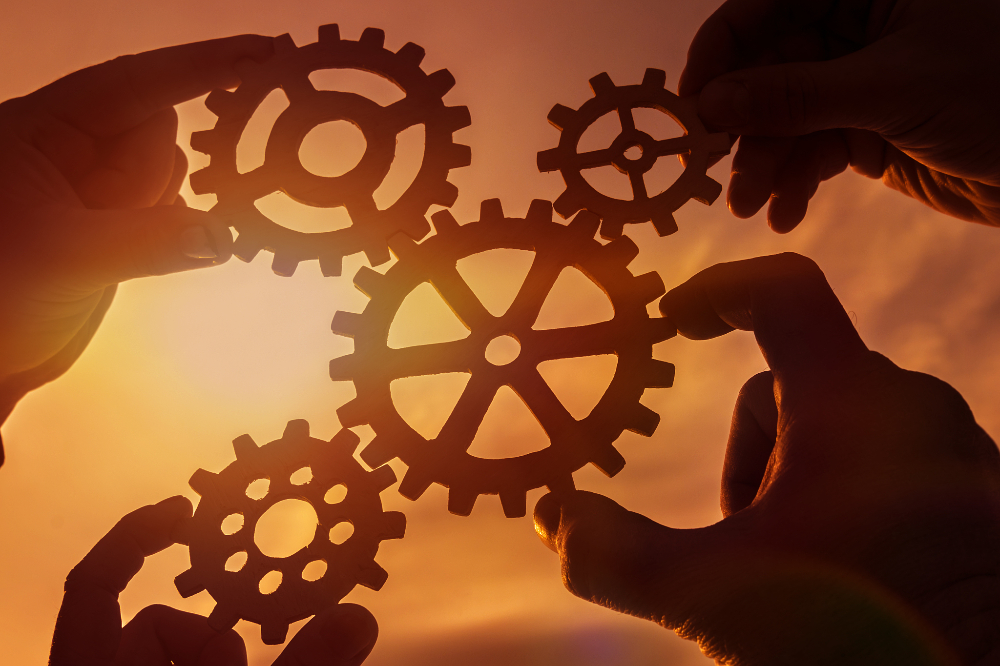 gears in the hands of people against the sky. sunset.