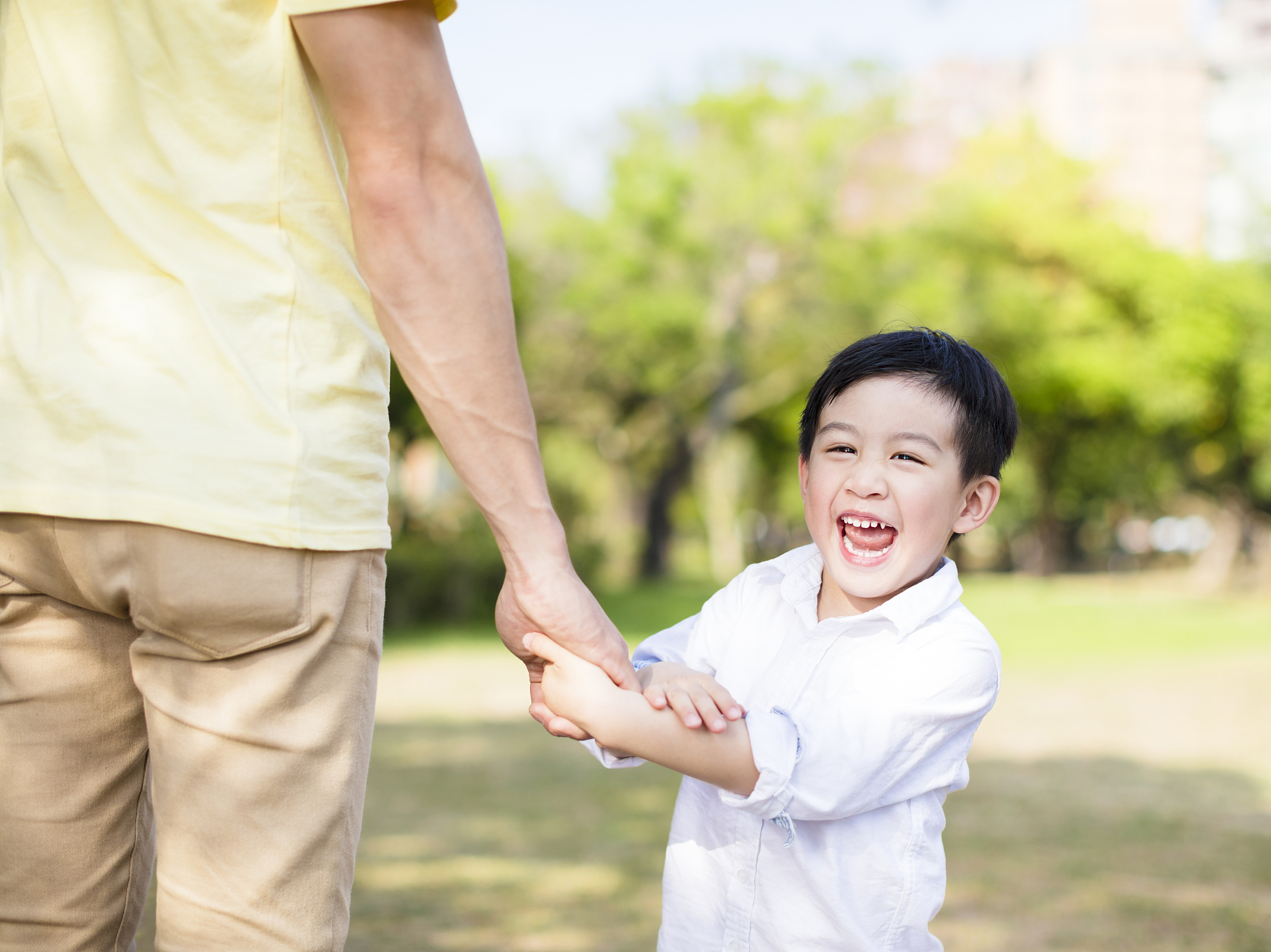 father holds the hand of little boy