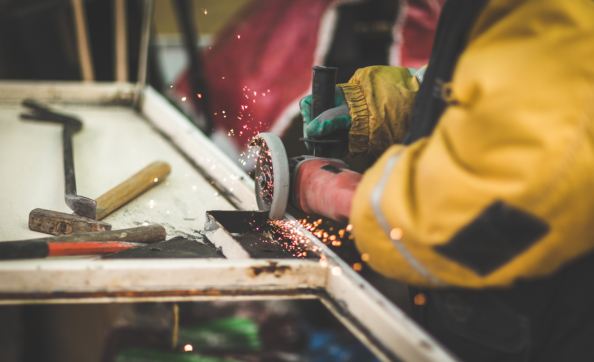 craftsman sawing metal with disk angle grinder in a warehouse.