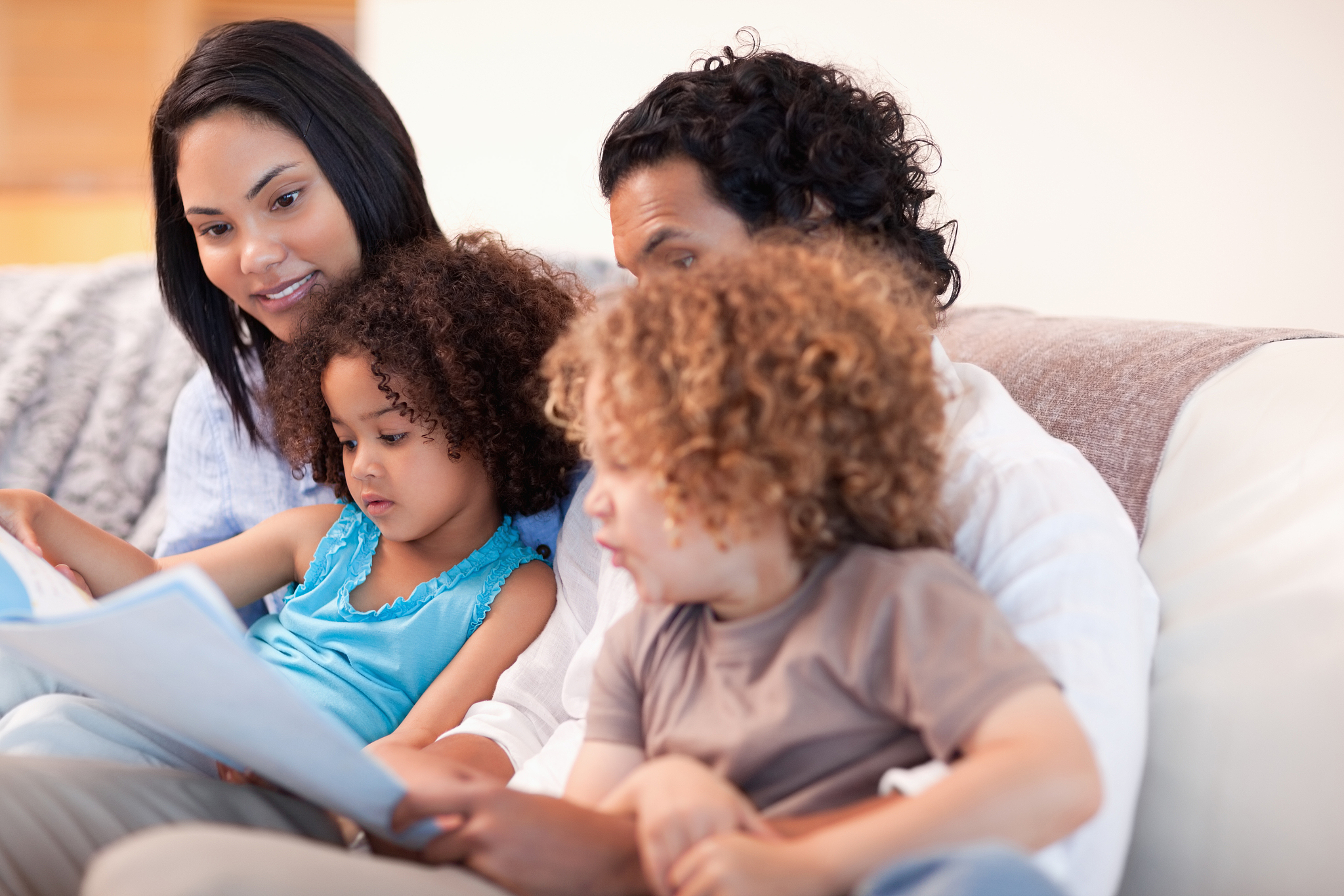 happy young family on the sofa looking at photo album together