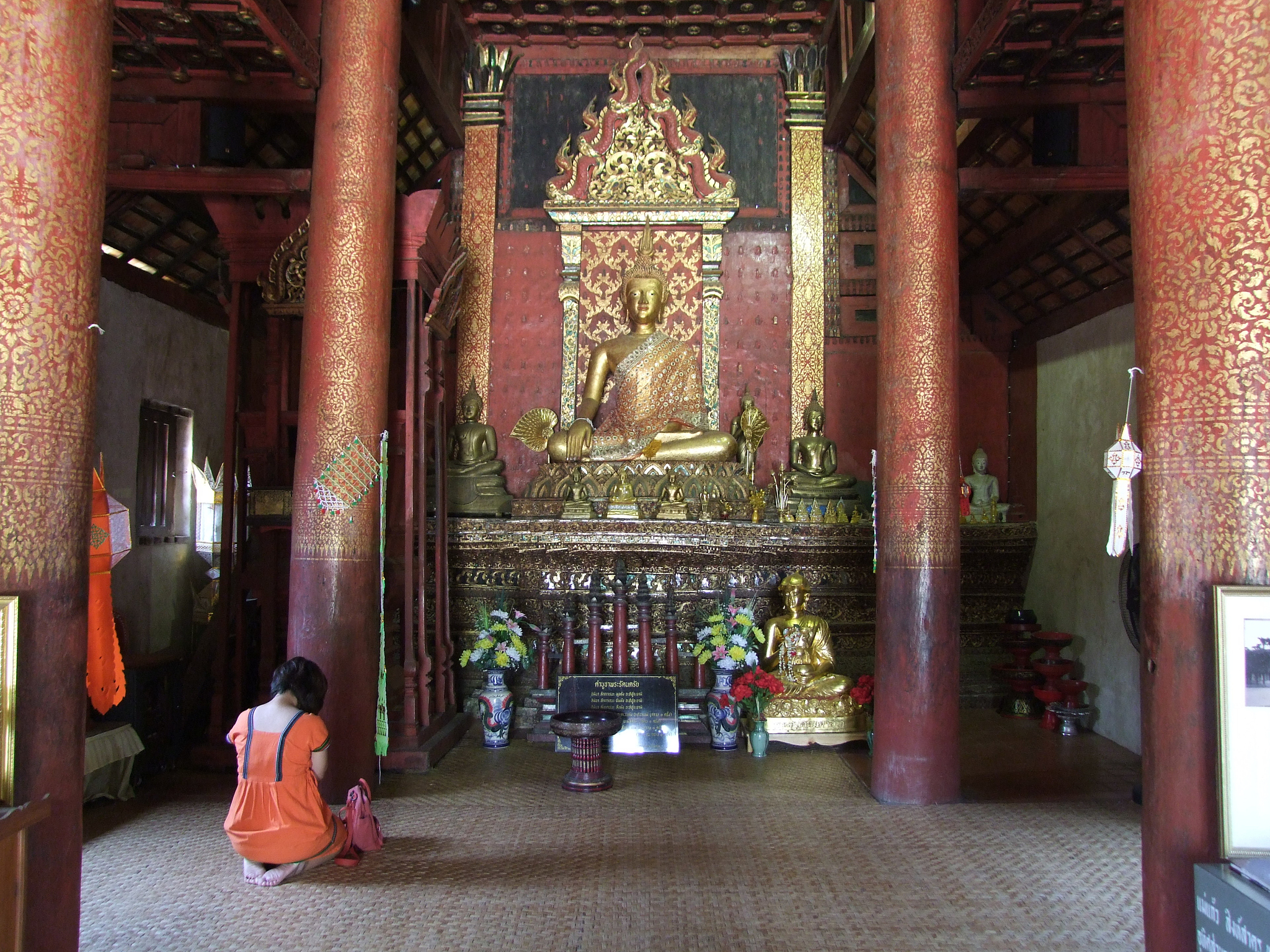 rear view of woman praying by statue in temple