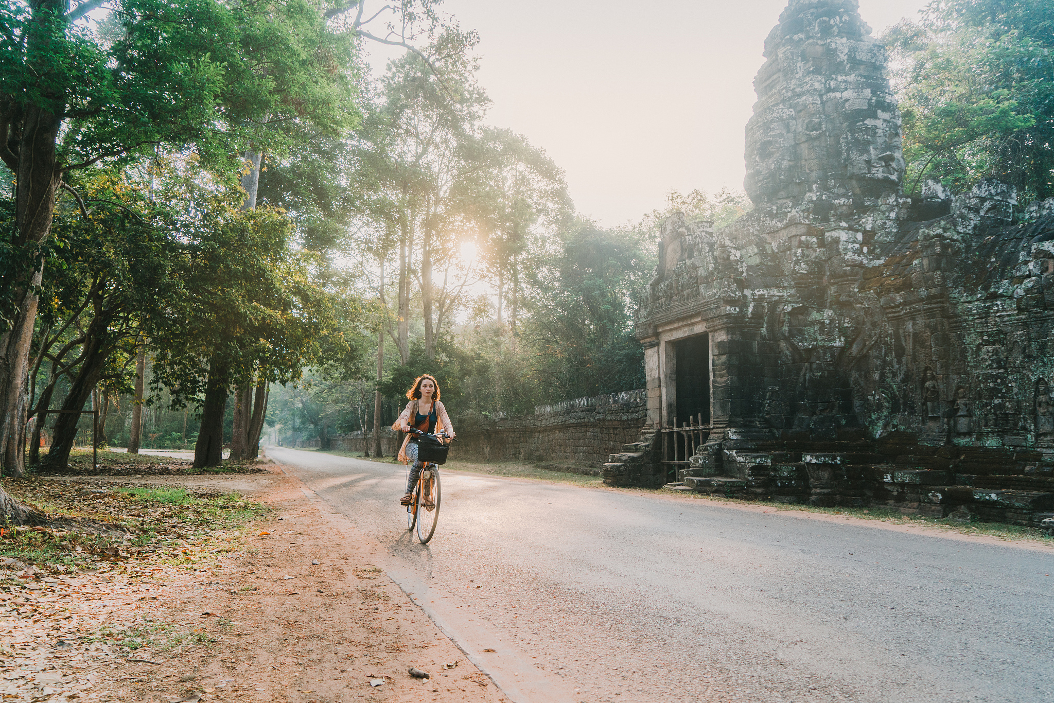 young caucasian woman riding  bicycle  in angkor wat