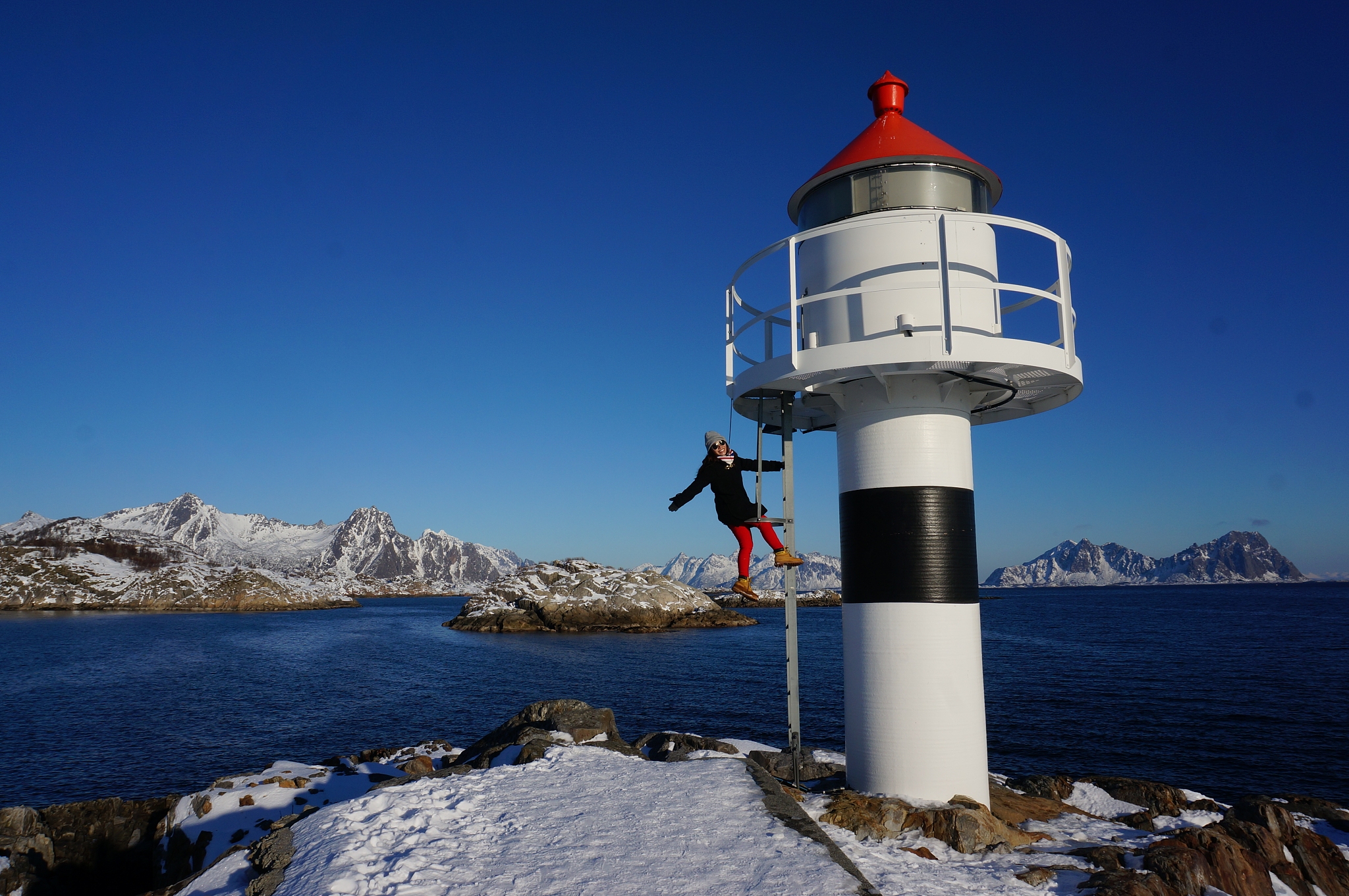 full length of woman standing by lighthouse on snow covered moun