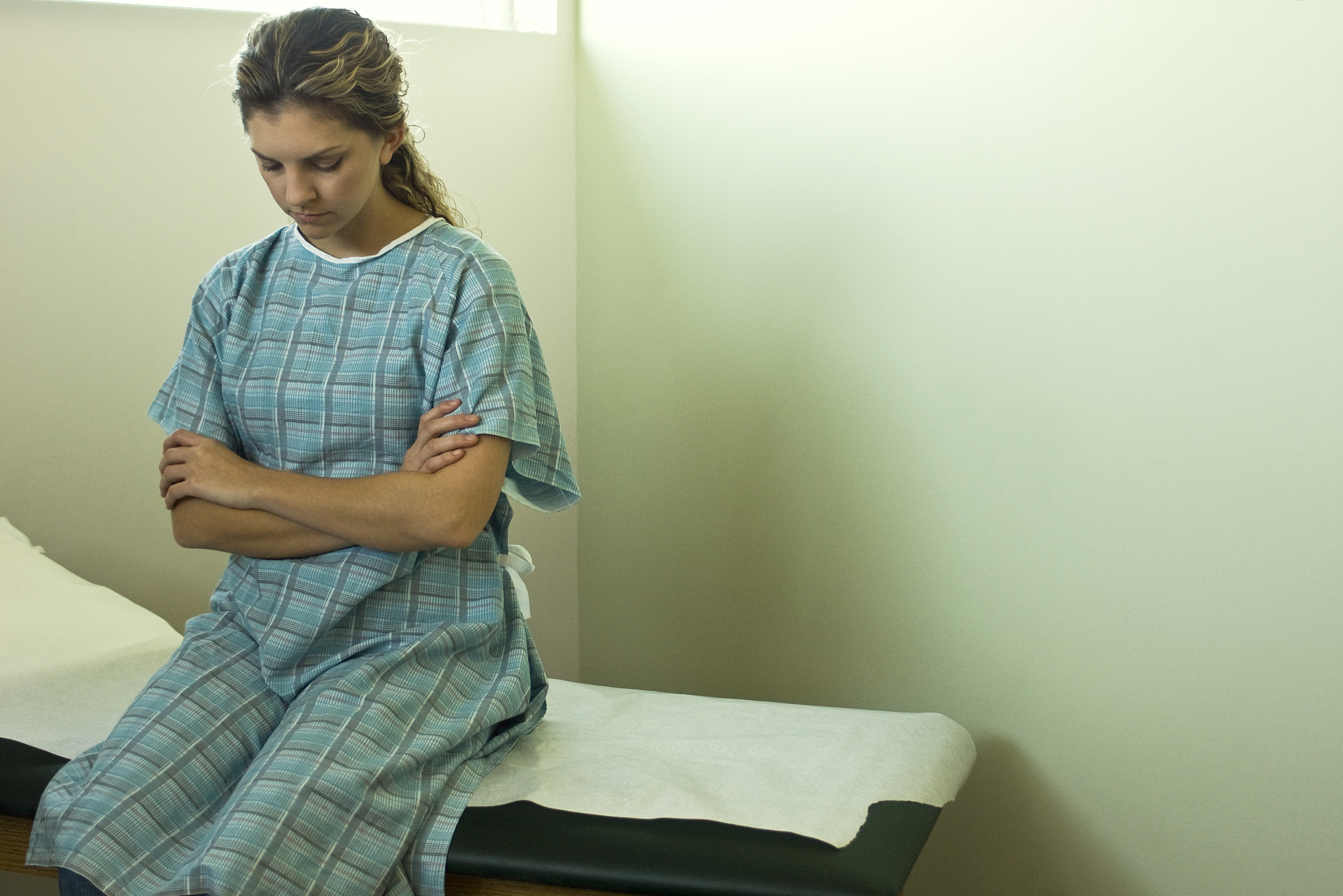 female patient sitting on examination table waiting for doctor