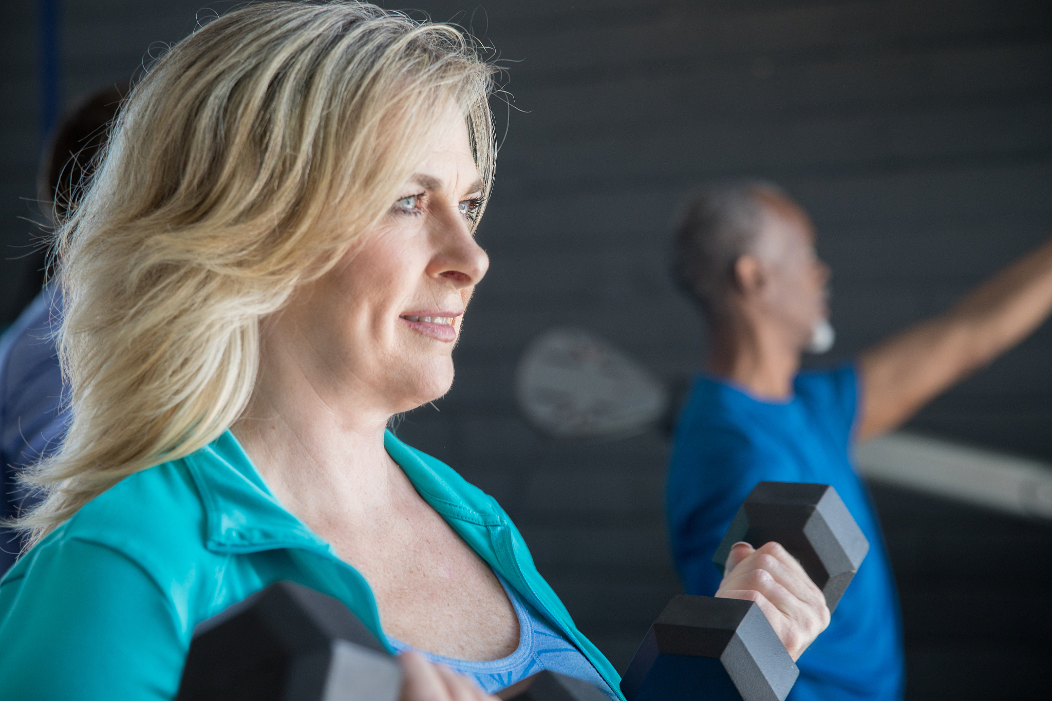 mature woman lifting weights in physical therapy center or gym