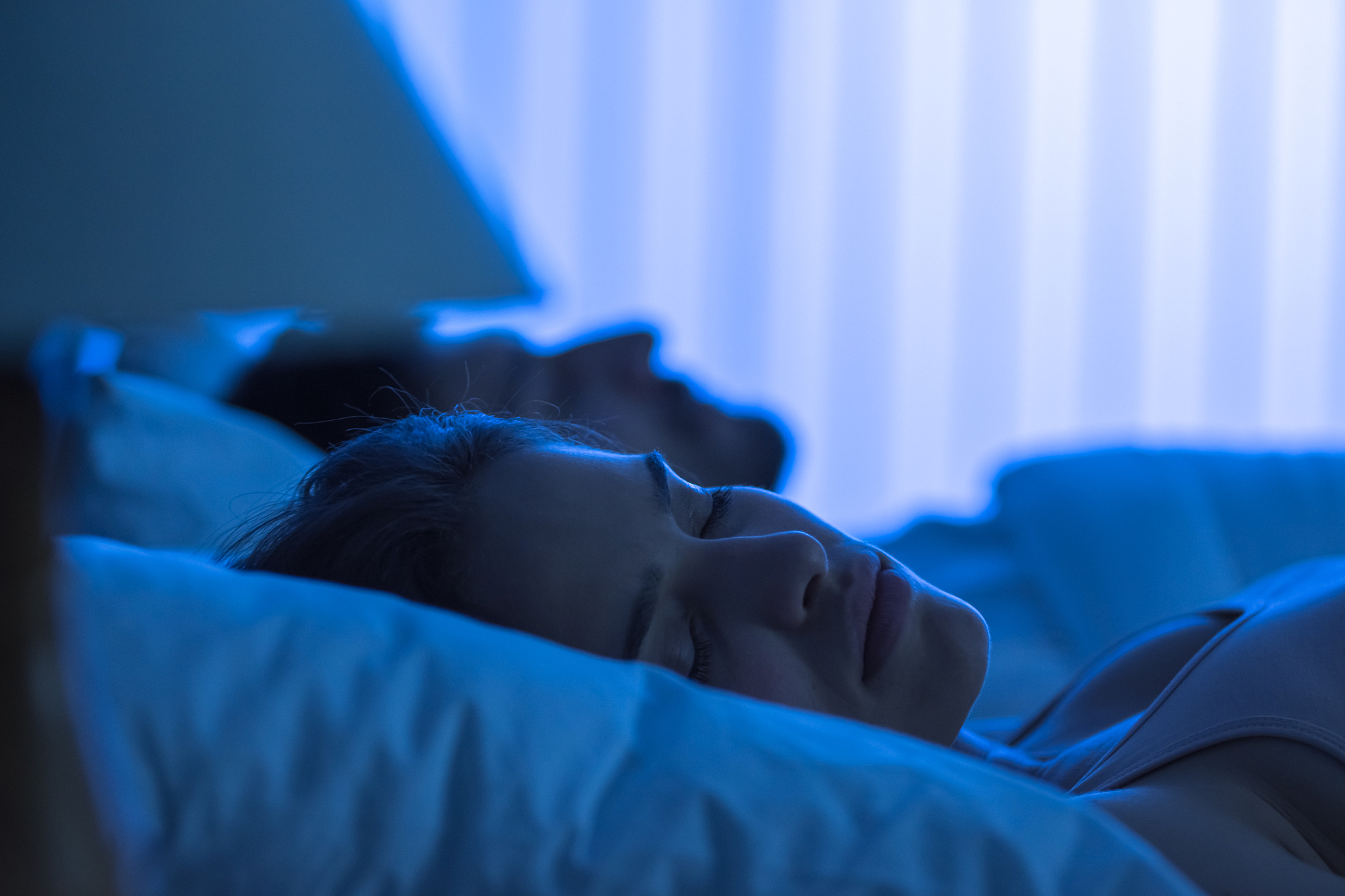 the cute woman sleeping near the man in the bed. night time