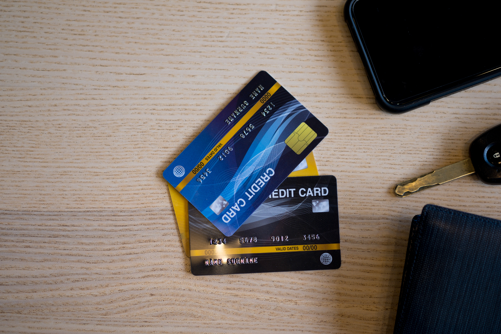 closeup of credit card with car keys, phone and wallet on wood t