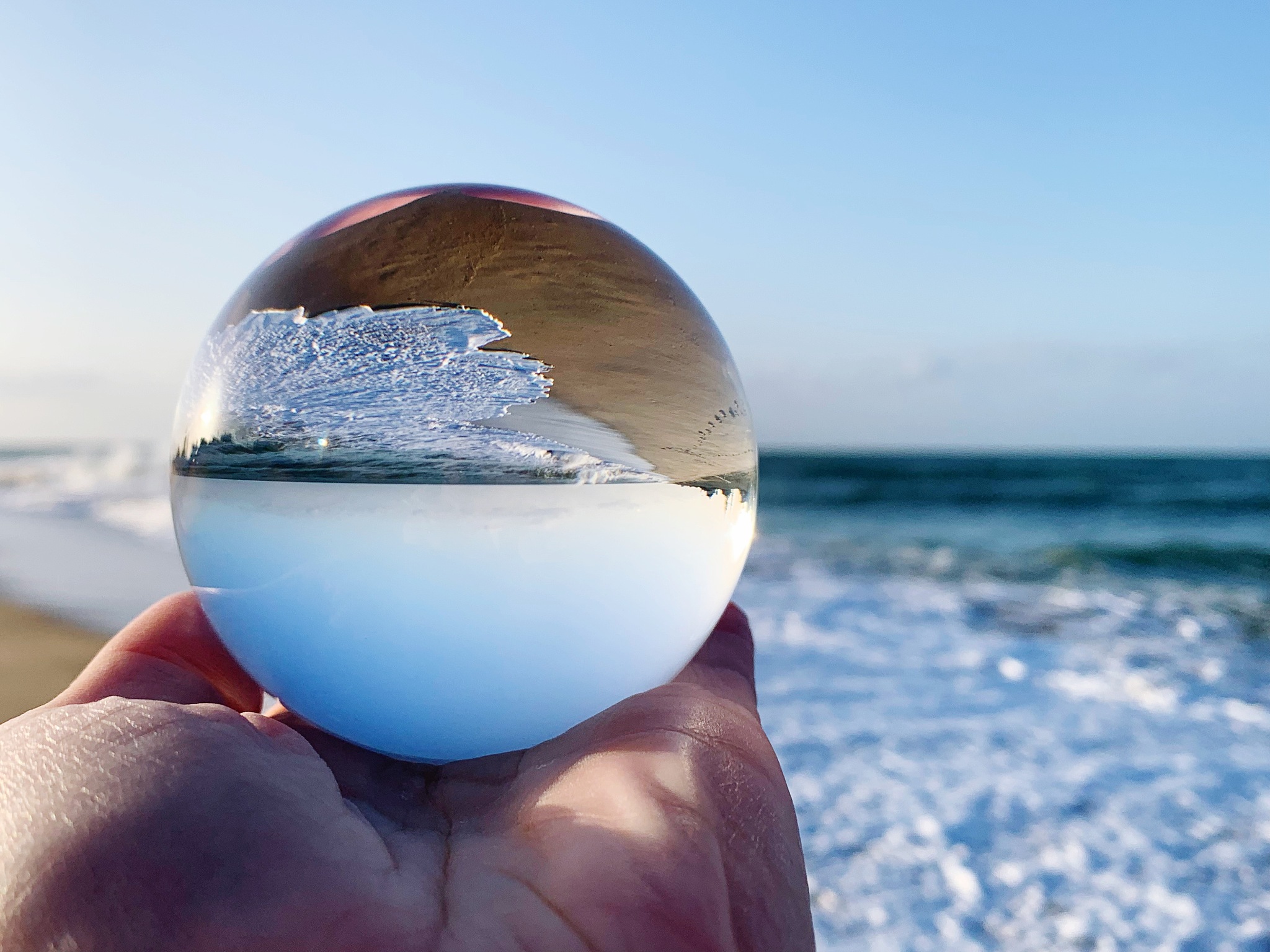 close-up of cropped hand holding crystal ball with reflection at