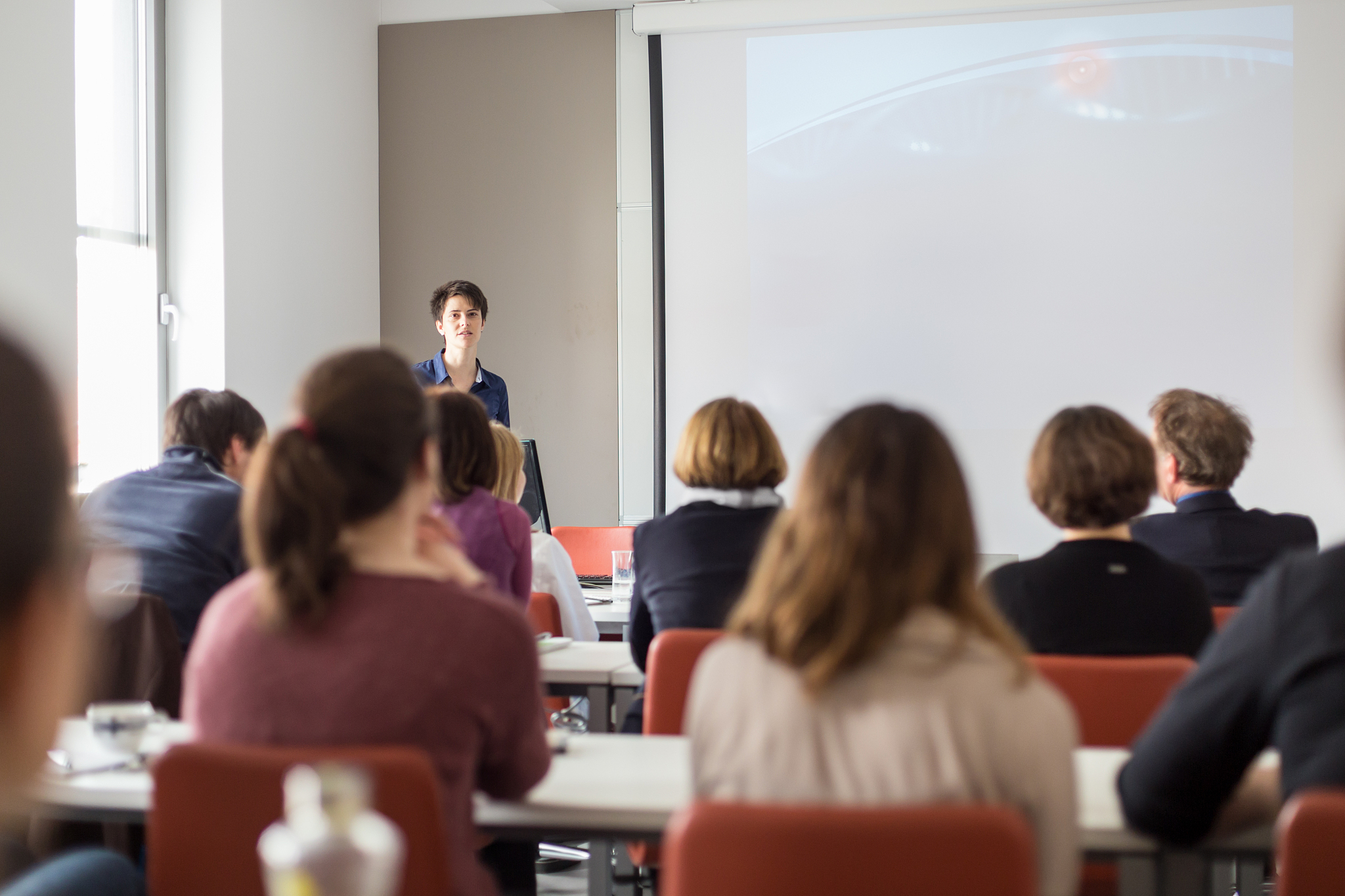 woman giving presentation in lecture hall at university.