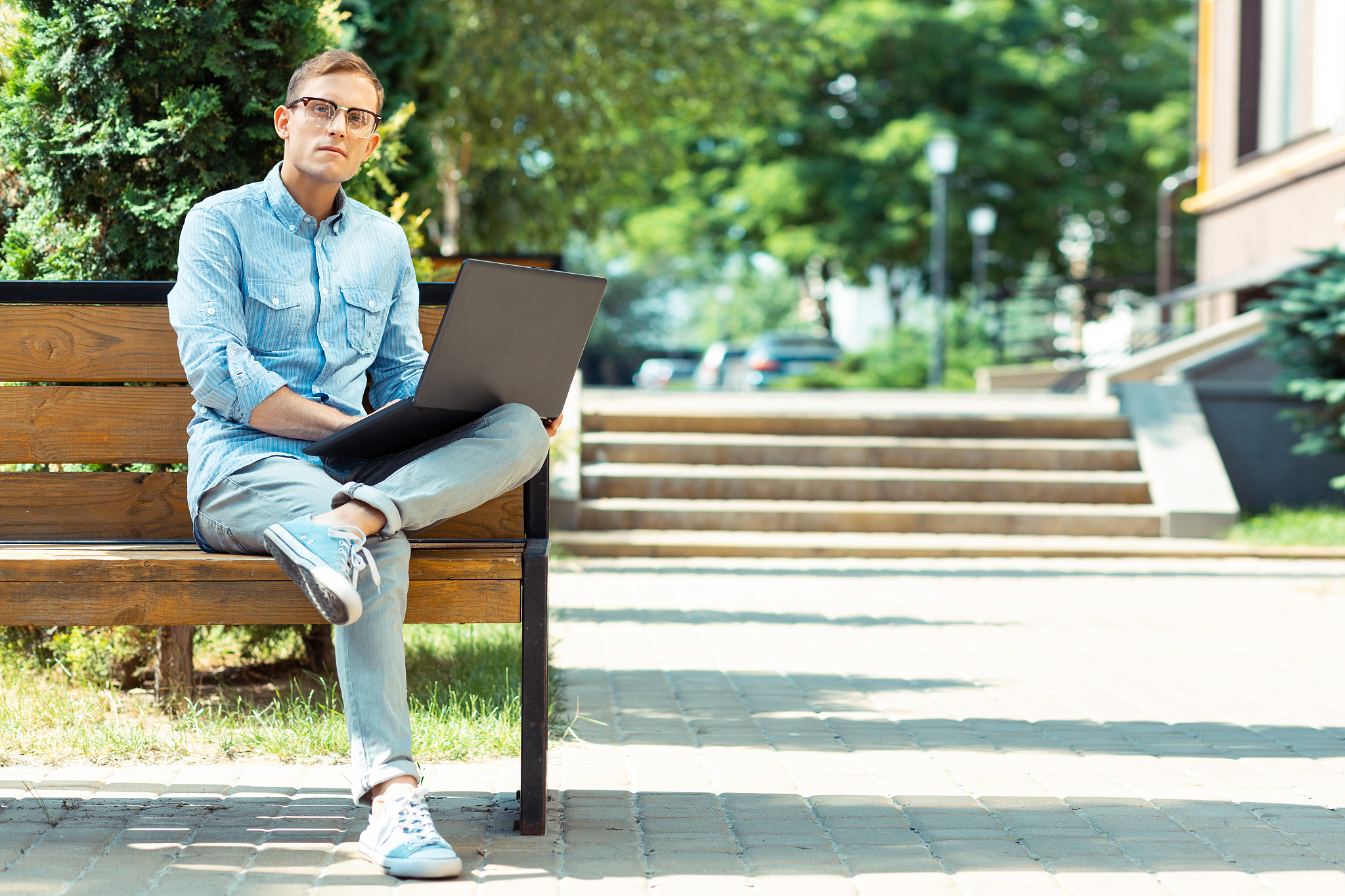 handsome stylish freelancer sitting on the bench with laptop